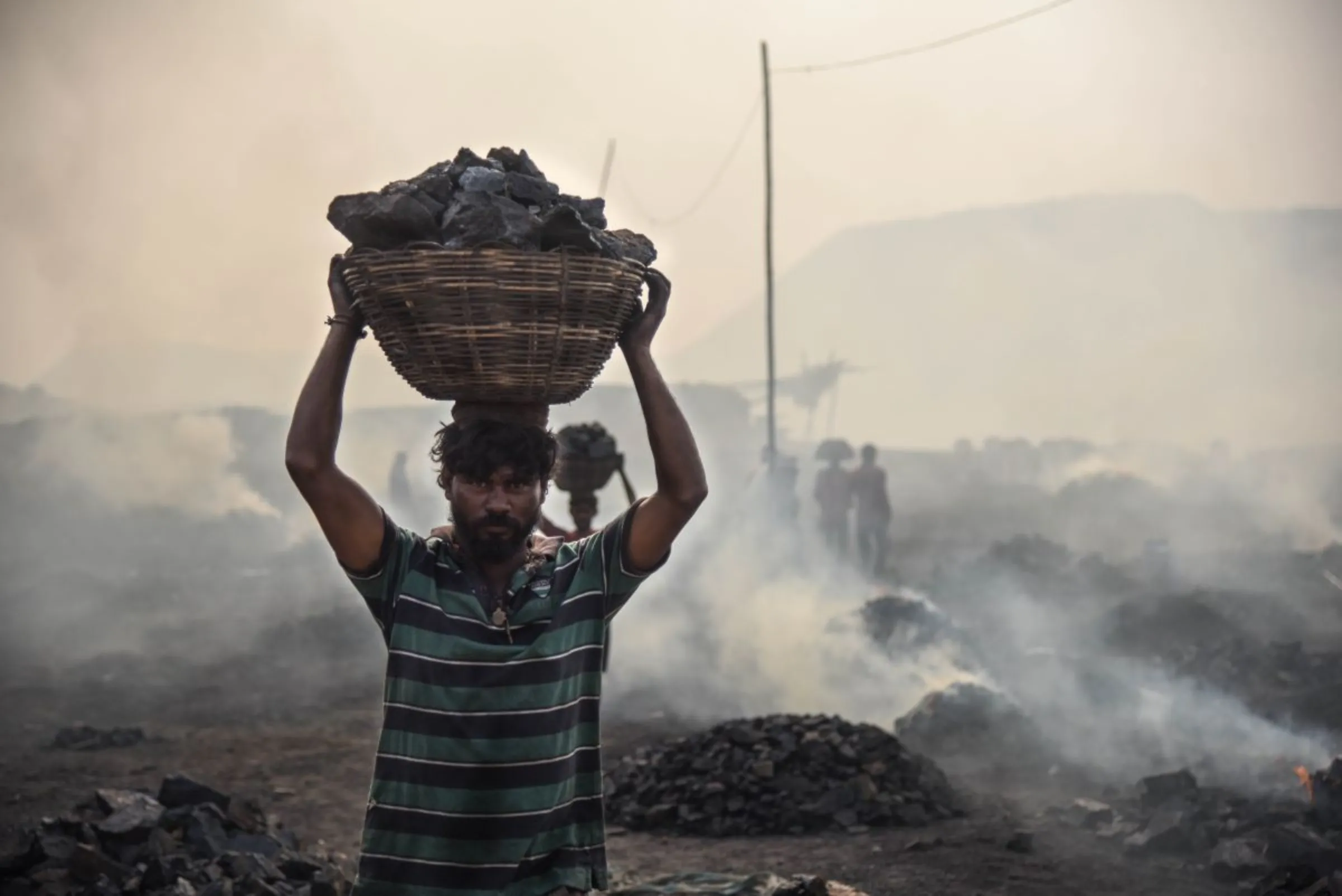 A man carries a basket of coal in a mining area of Jharia coalfield, India, November 11, 2022. Thomson Reuters Foundation/Tanmoy Bhaduri