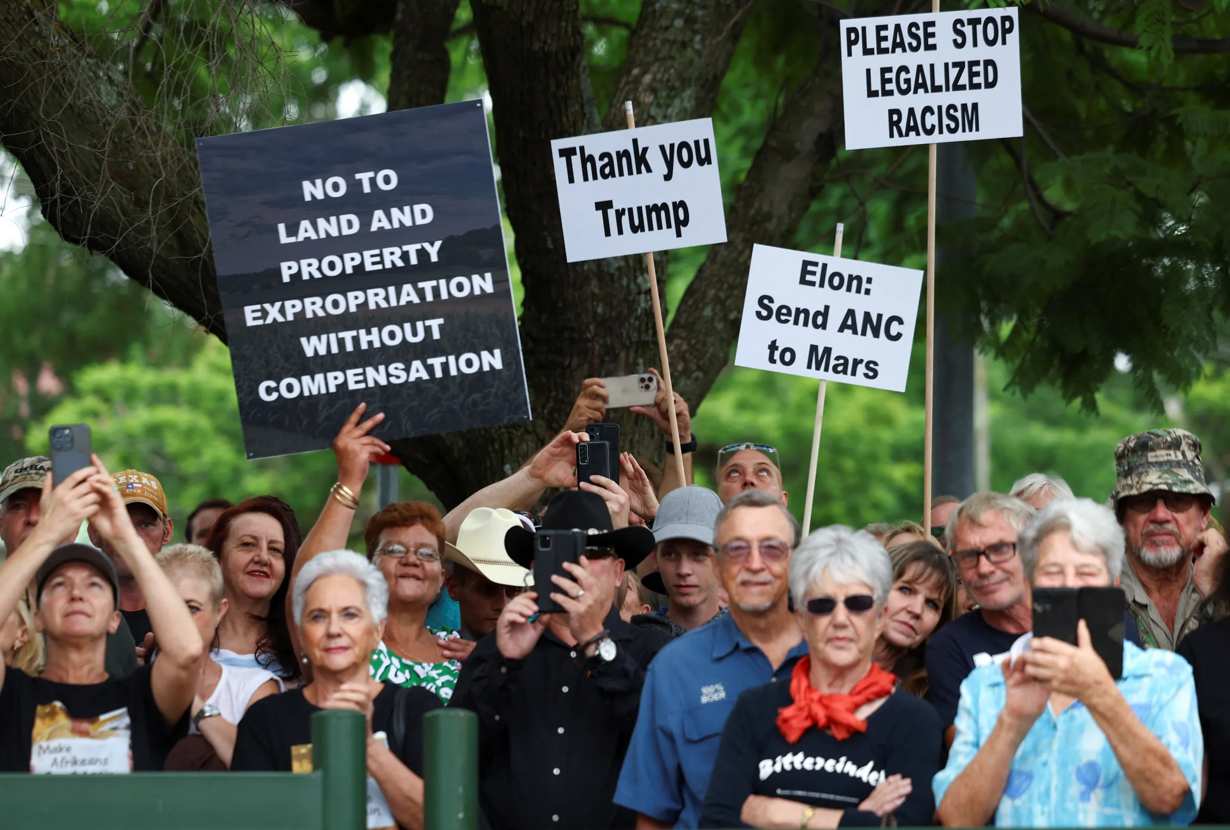 Demonstrators hold placards in support of U.S. President Donald Trump's stance against what he calls racist laws, land expropriation, and farm attacks, outside the American Embassy in Pretoria, South Africa, February 15, 2025. REUTERS/Siphiwe Sibeko