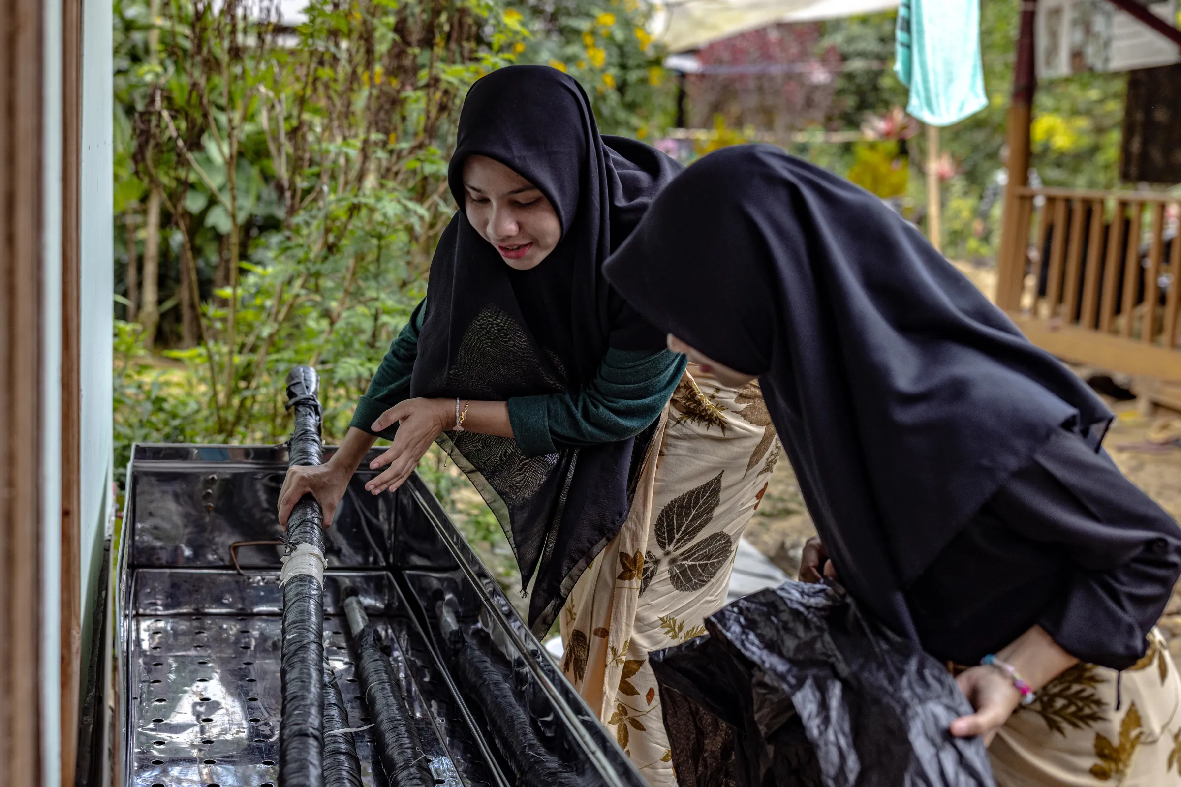 Members of the Ambu Halimun community steam rolls of fabric using a one-meter-long steamer, allowing the leaves and flowers to release tannins that create natural colors on the fabric, in Citalahab Central, West Java, Indonesia, on July 16, 2025. Thomson Reuters Foundation/Yudha Baskoro