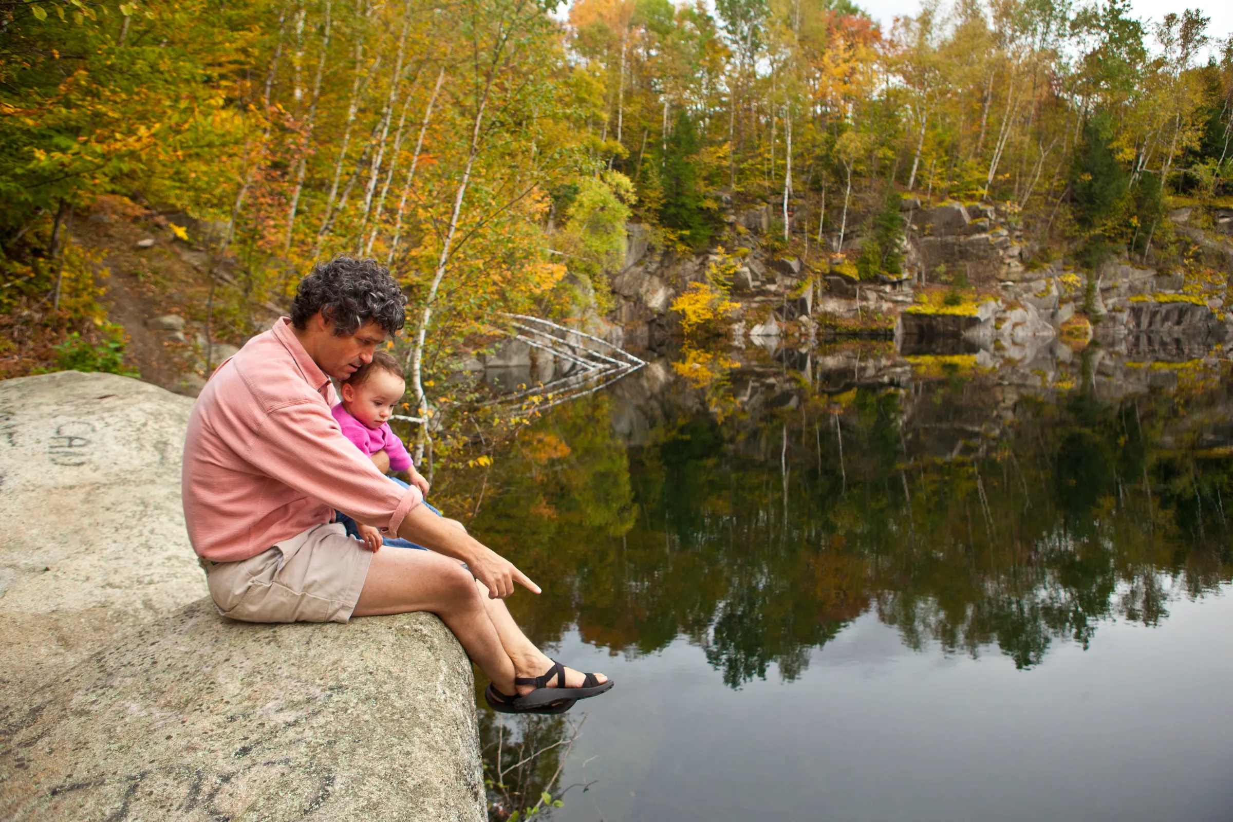 A man and his daughter sit above a pond in Barre Town Forest in Barre, Vermont.