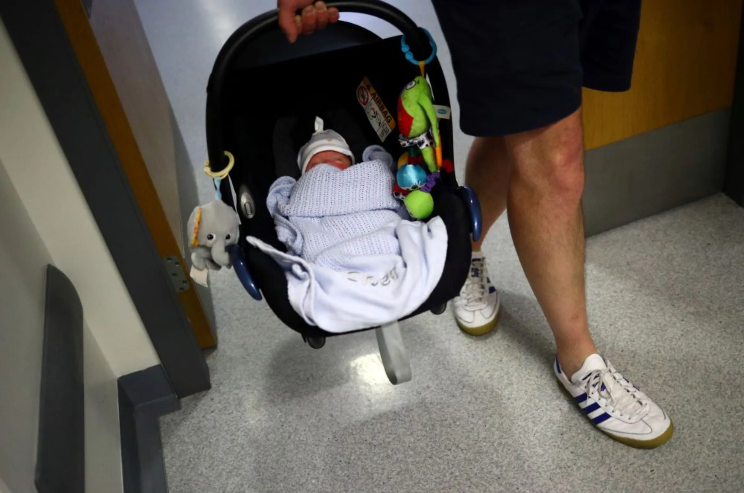 A baby who was born prematurely and is now nine weeks old, is carried in a car seat by his father as they leave hospital after being discharged from the Lancashire Women and Newborn Centre of Burnley General Hospital in East Lancashire, in Burnley, Britain, June 22, 2020
