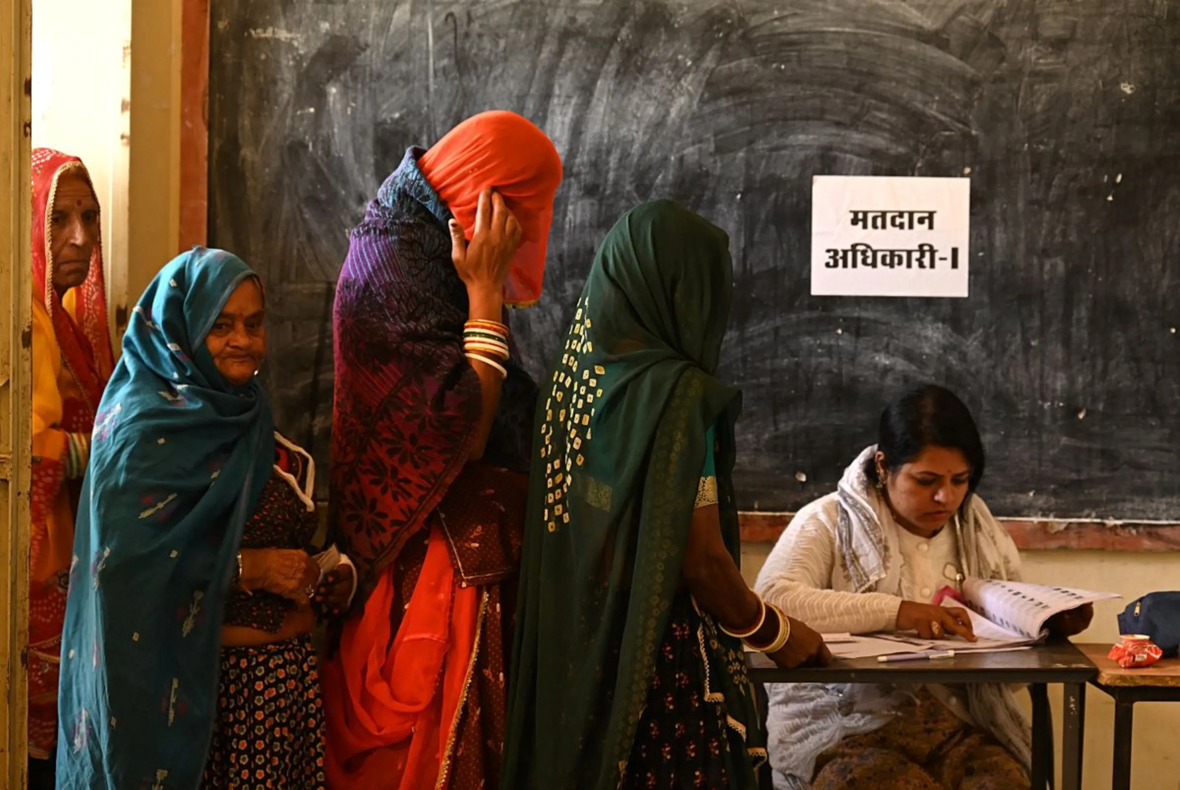 Women wait in a queue to cast their votes at a polling station during Rajasthan state assembly election in Ajmer, India, November 25, 2023