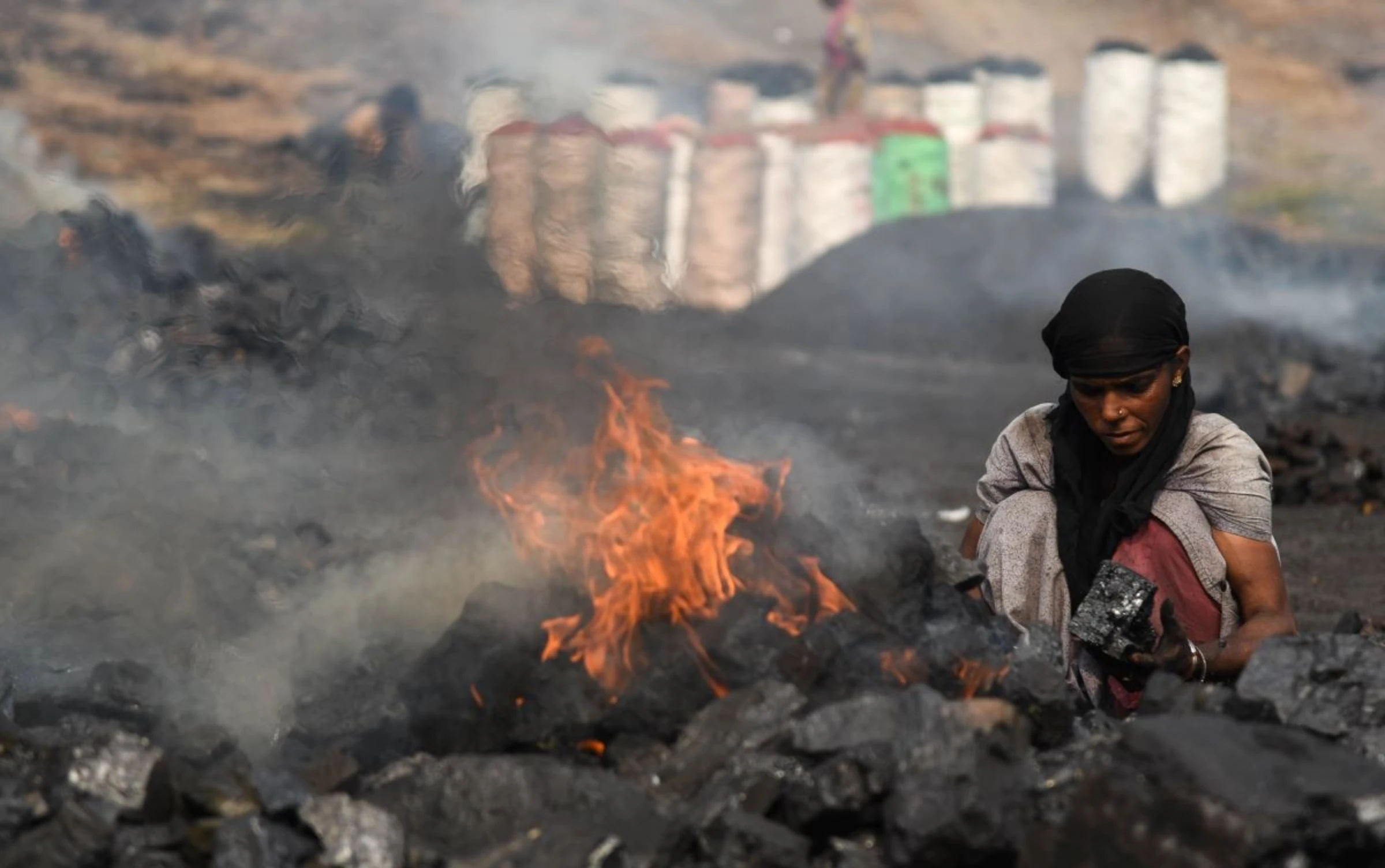Coal scavenger Anita Devi burns coal before selling it for use at a depot in a mining area of Jharia coalfield, India, November 11, 2022. Thomson Reuters Foundation/Tanmoy Bhaduri