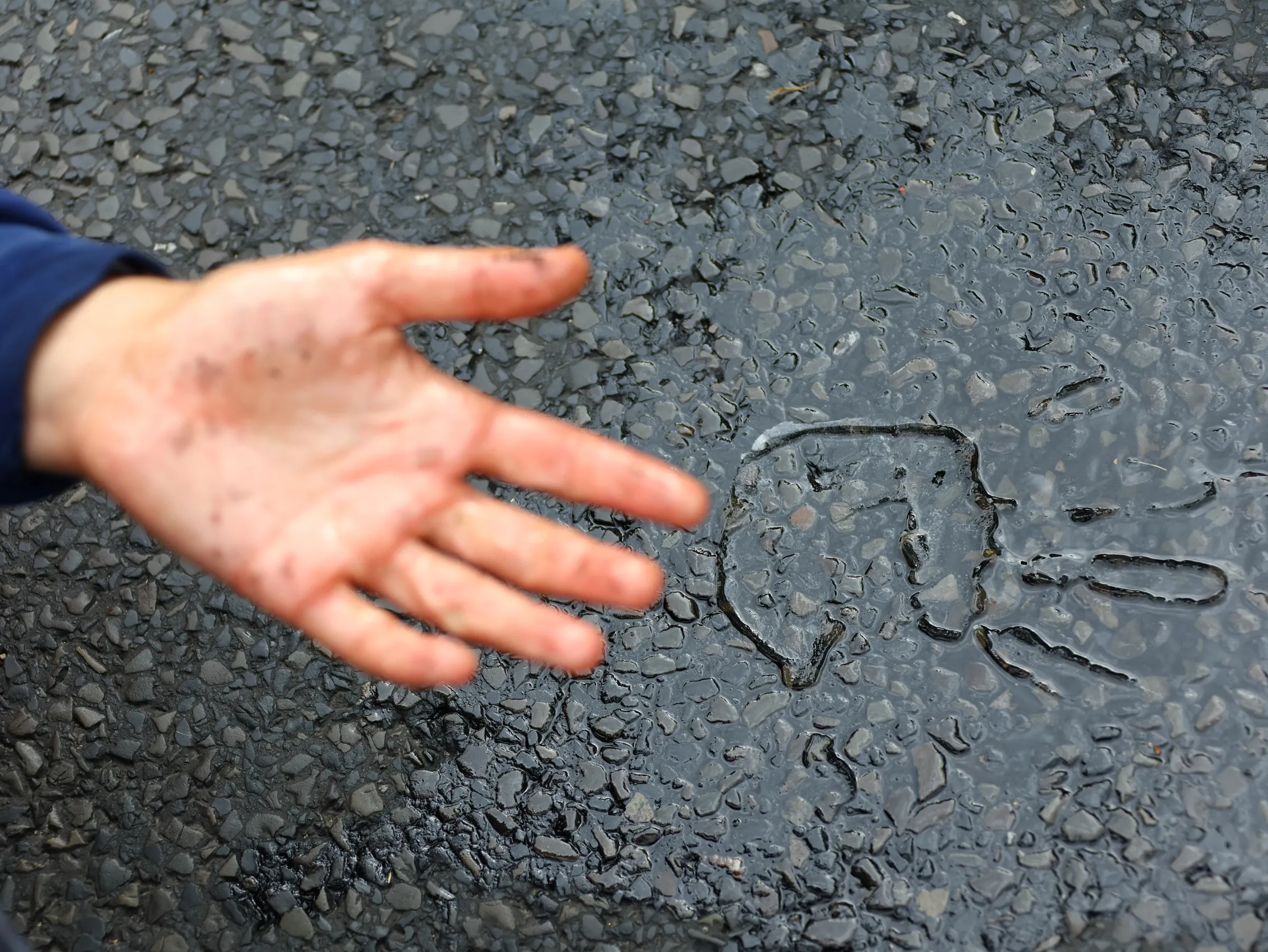The shape of the hand is seen on the glue on the road as 'Letzte Generation' (Last Generation) activist block a road under the slogan 'Let's stop the fossil madness!' for an end to fossil fuels and against oil drilling in the North Sea, in Berlin, Germany,