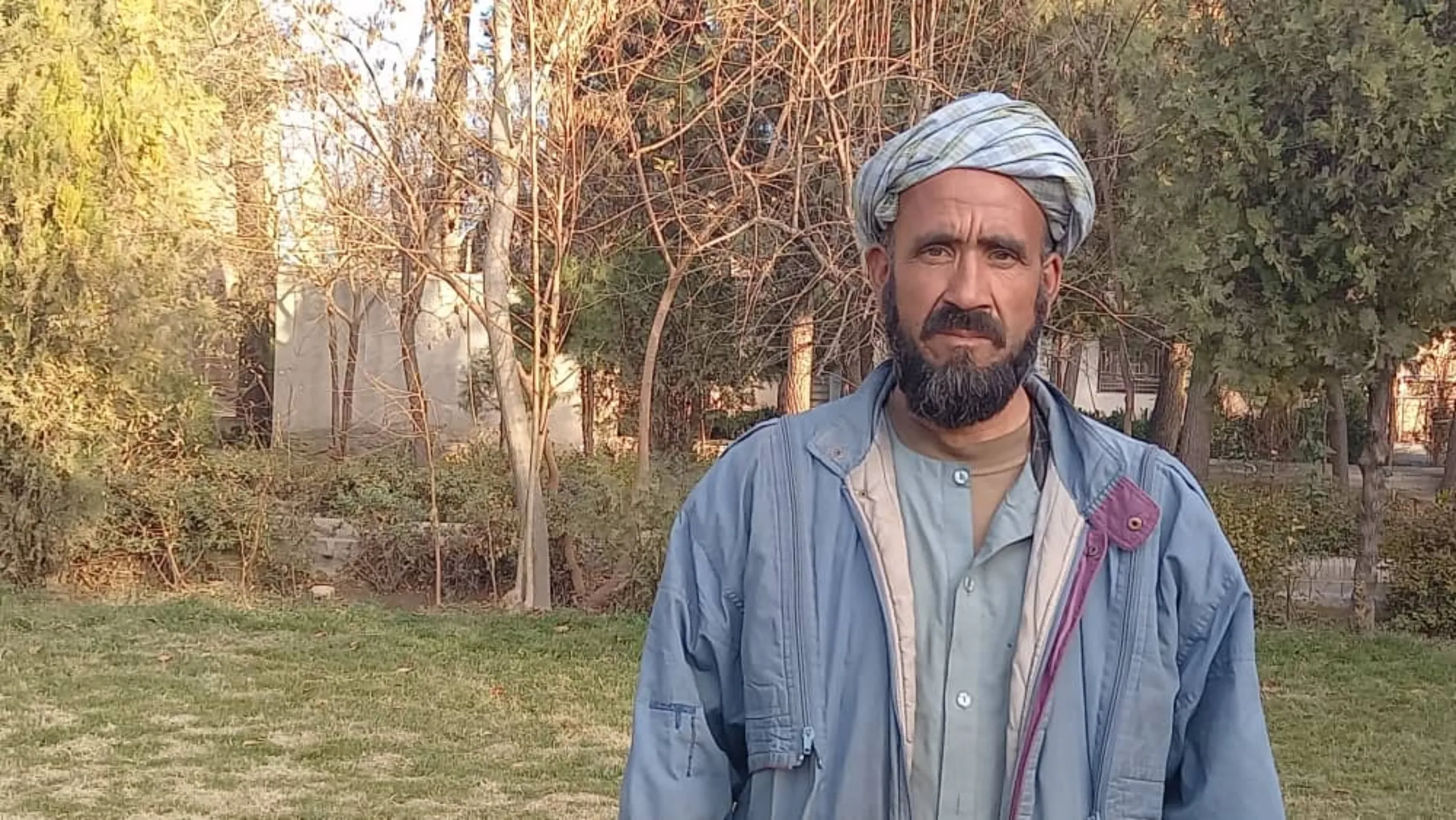 An Afghan farmer stands  outside the office of the U.N.'s Food and Agriculture Organization in Herat, surrounded by trees