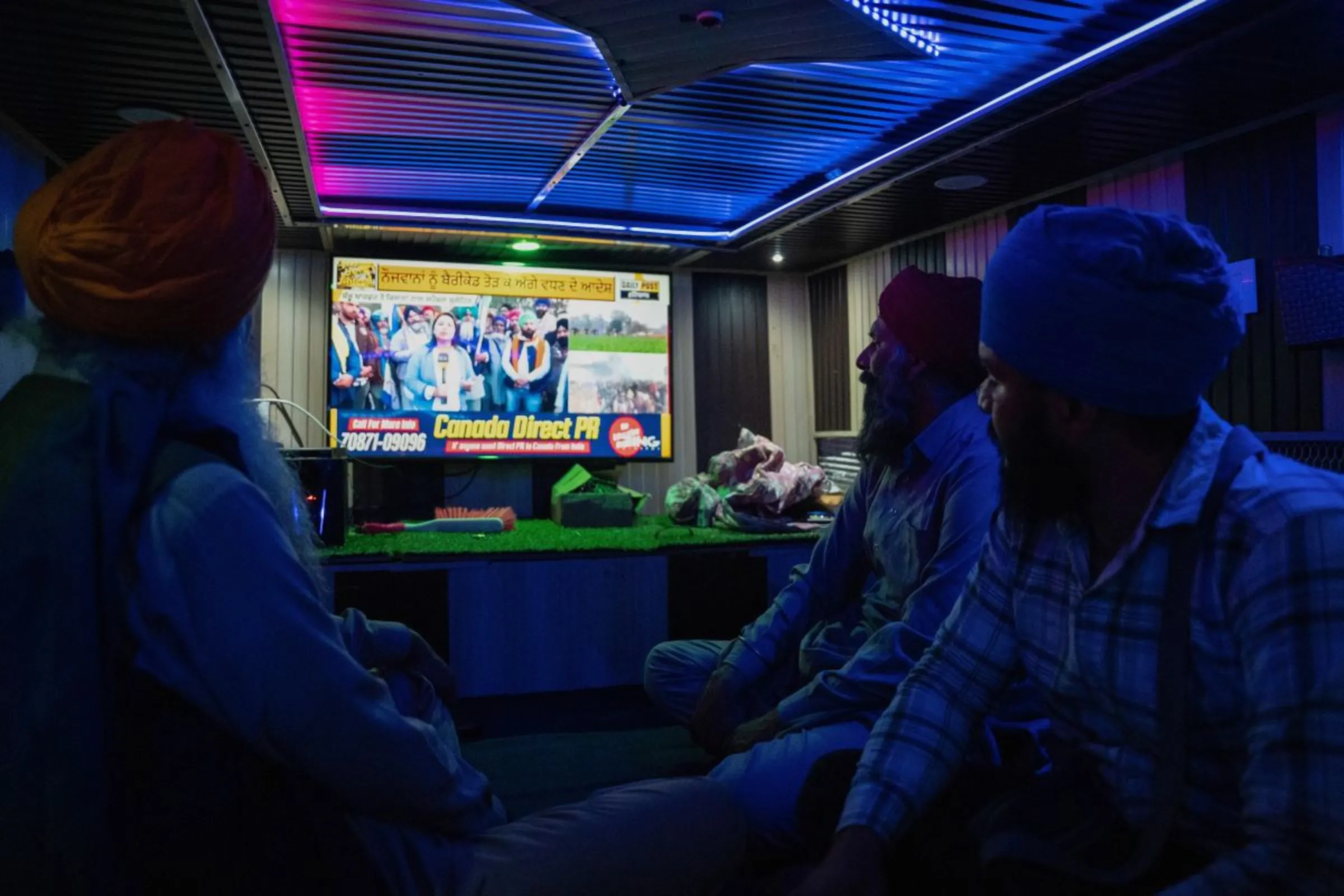 Protesting farmers watch the news on a television set inside a tractor trolley as mobile internet services are cut at Shambhu Barrier, India, February 21, 2024. Thomson Reuters Foundation/Mehran Firdous