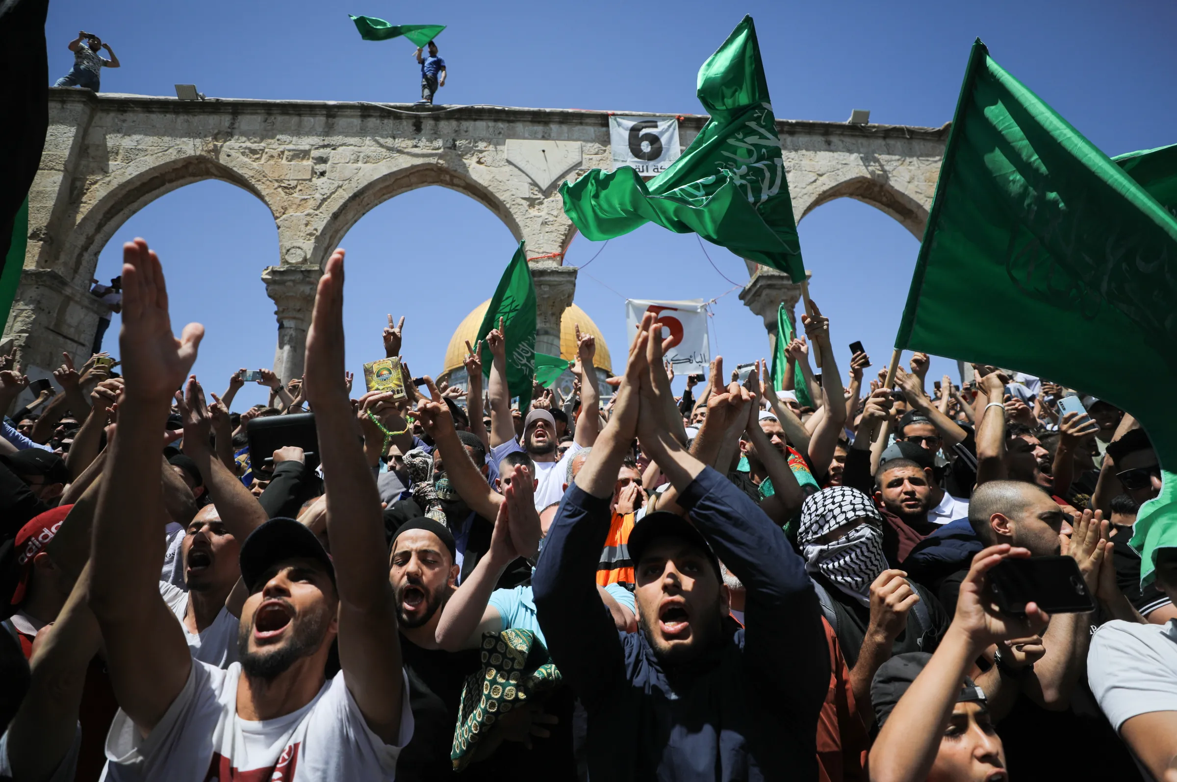 People hold Hamas flags as Palestinians gather after performing the last Friday of Ramadan to protest over the possible eviction of several Palestinian families from homes on land claimed by Jewish settlers in the Sheikh Jarrah neighbourhood, in Jerusalem's Old City, May 7, 2021. REUTERS/Ammar Awad