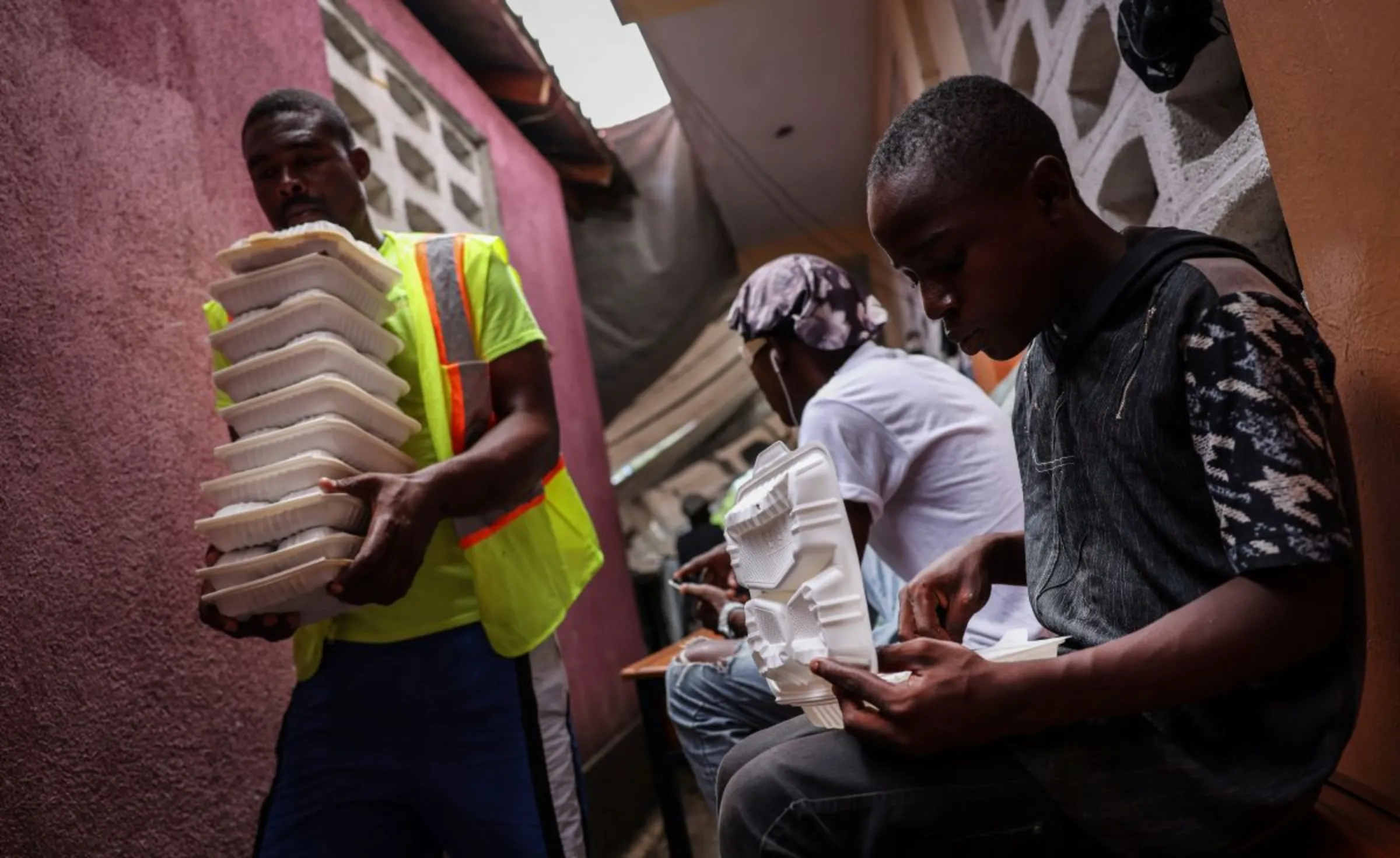 A volunteer carries food distributed by a community action center, with the assistance of the United Nations World Food Programme, into a shelter in Port-au-Prince, Haiti, May 3, 2024. REUTERS/Ricardo Arduengo