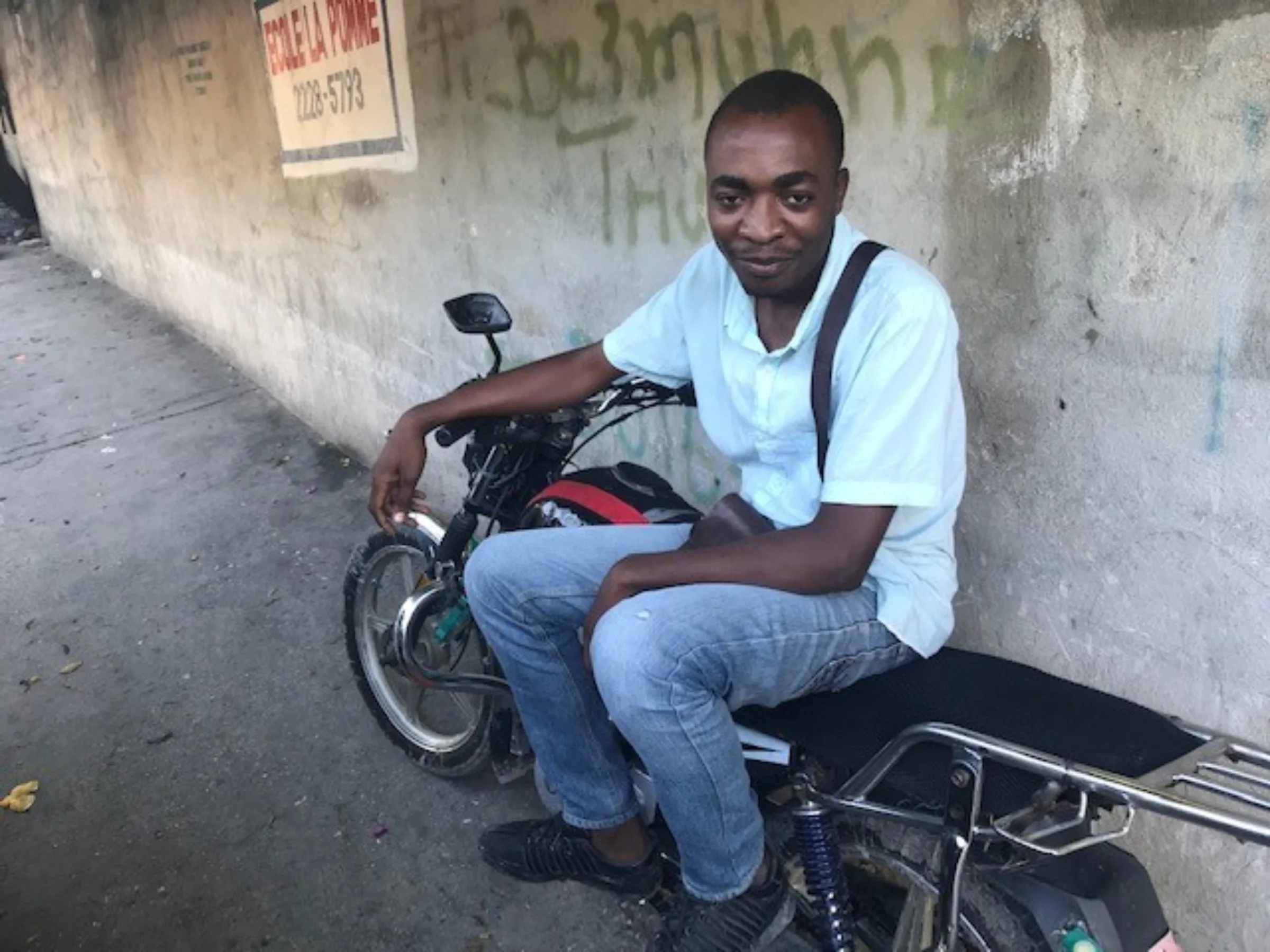 Haitian Johnny Decius, a motorbike taxi driver, in the capital Port-au-Prince, Haiti. November 14, 2022. Thomson Reuters Foundation/Jennifer D. Delva
