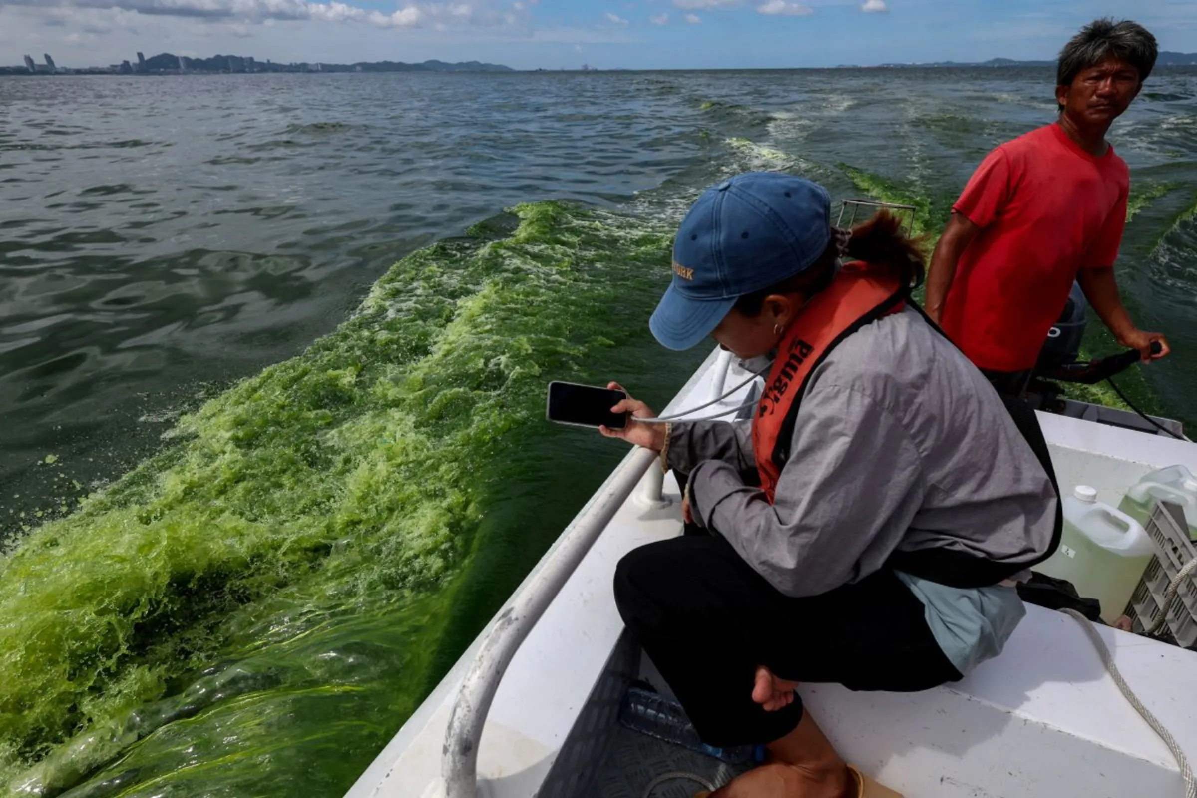 A marine scientist from Kasetsart University takes photos of green sea water caused by plankton bloom known to kill marine life, at Chonburi's coastline, Thailand, September 14, 2023