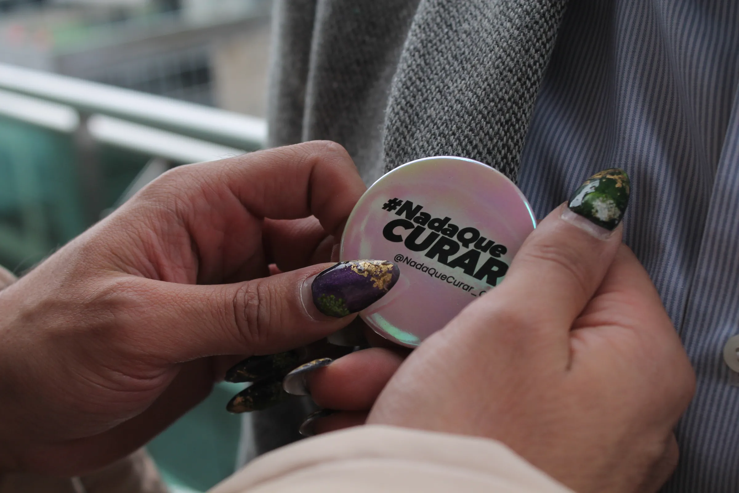 Colombian trans activist Danne Belmont puts a pin that reads 'Nada que curar' (nothing to heal, in Spanish) on the jacket of Juan Viana, a gay man who underwent so-called 'conversion therapy' as a teenager in Bogotá, on July 24, 2025. Thomson Reuters Foundation/Enrique Anarte