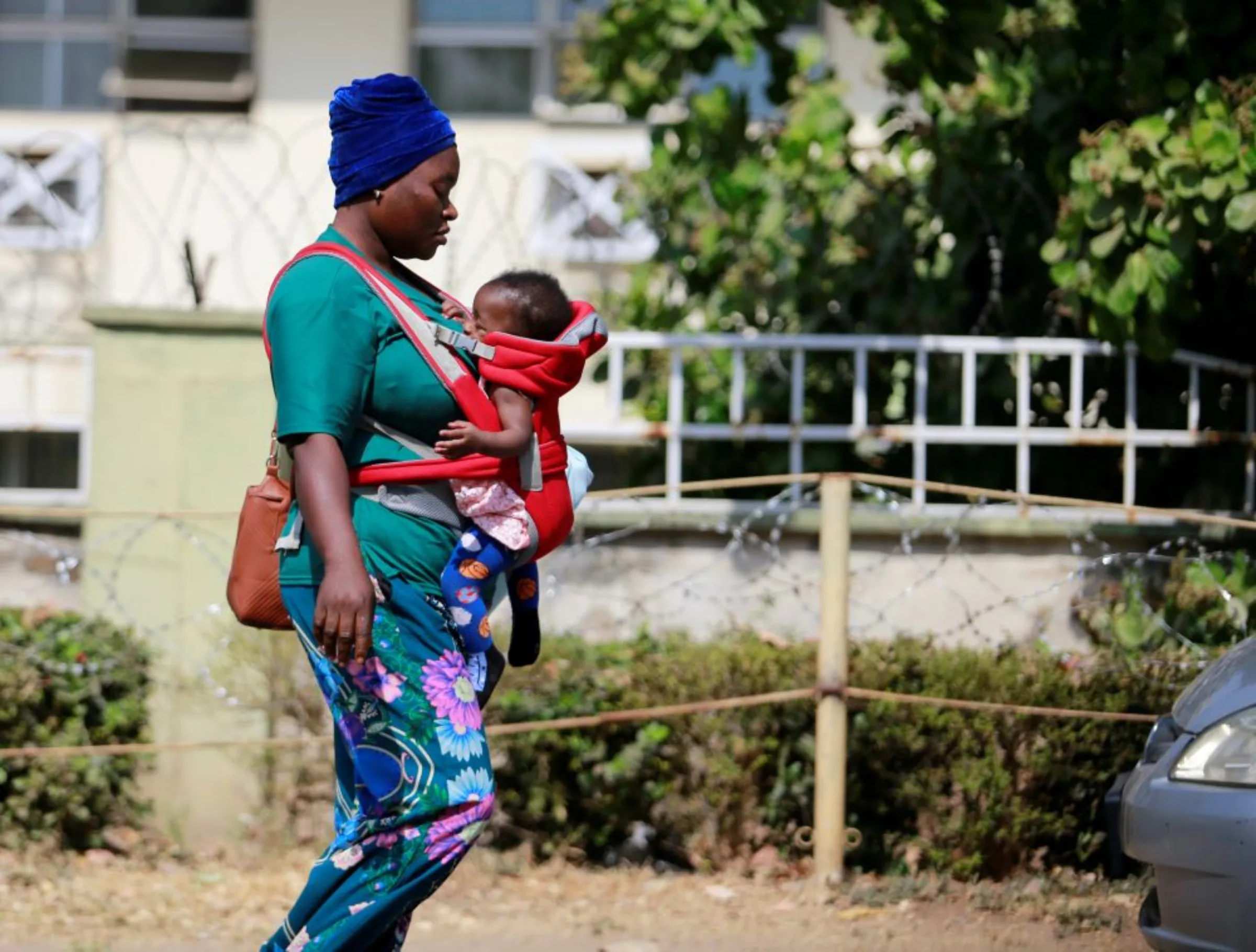 A mother carries her baby in a strap carrier bag outside the Wuse general Hospital in Abuja, Nigeria January 26, 2022