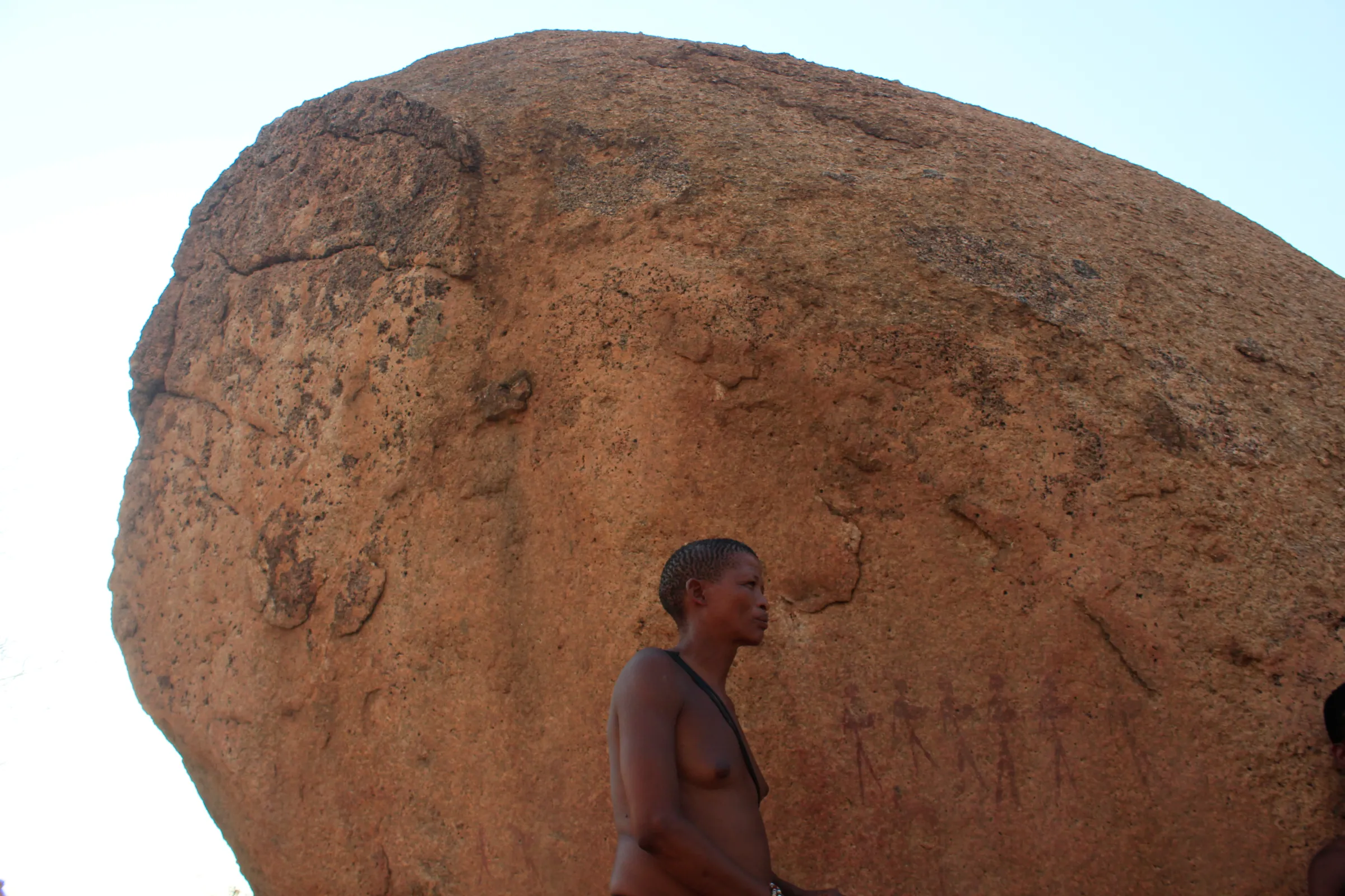 Johannes Ikun Nani stands in front of a boulder displaying ancient San rock at the Omandumba farm in the central region of Namibia, September 30, 2022