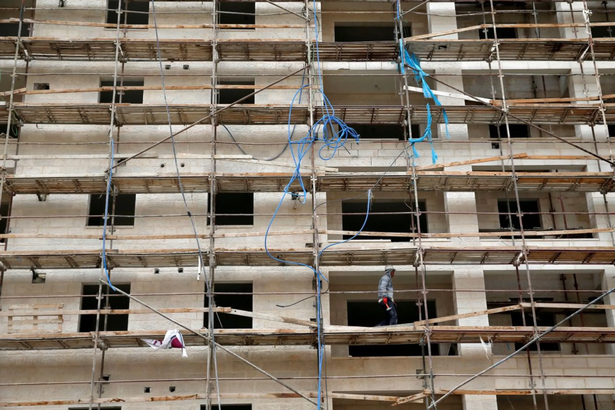 A worker walks on scaffoldings in a construction site at the Israeli settlement of Har Homa, in the occupied West Bank December 28, 2016. REUTERS/Baz Ratner