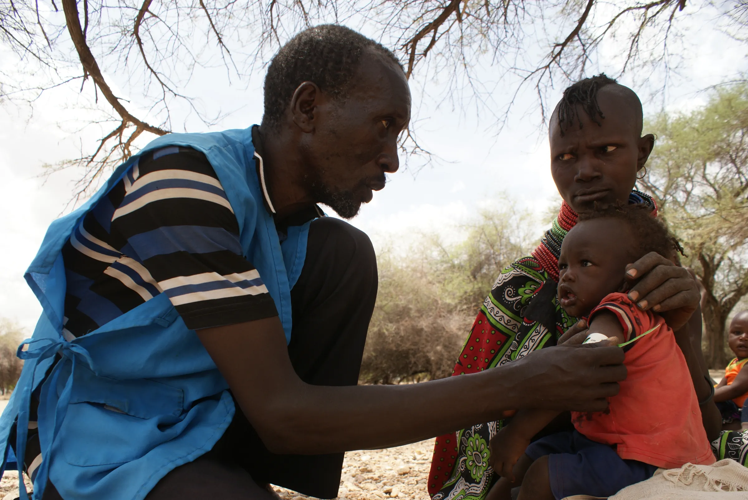 A community health worker checks a child for malnutrition during a community medical clinic in  northern Kenya