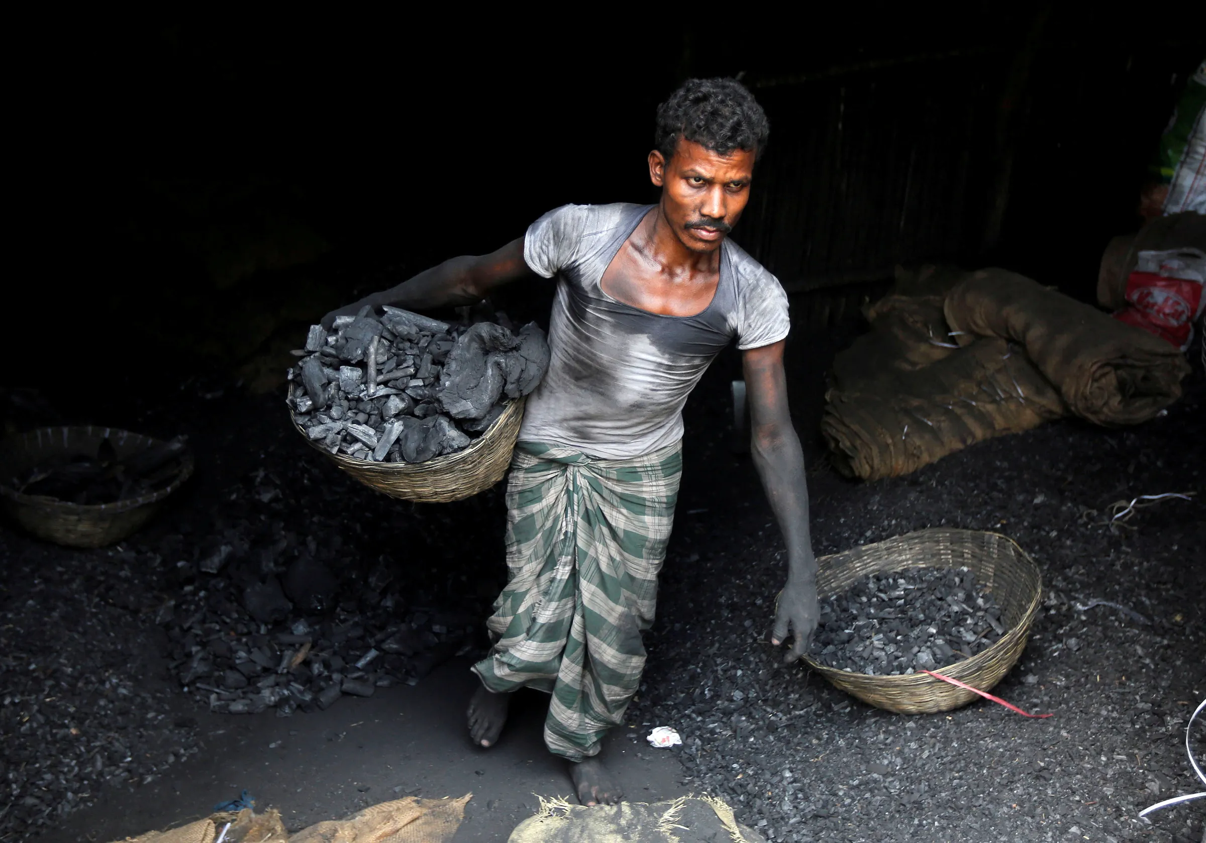 A worker carries coal in a basket in a industrial area in Mumbai, India May 31, 2017. REUTERS/Shailesh Andrade