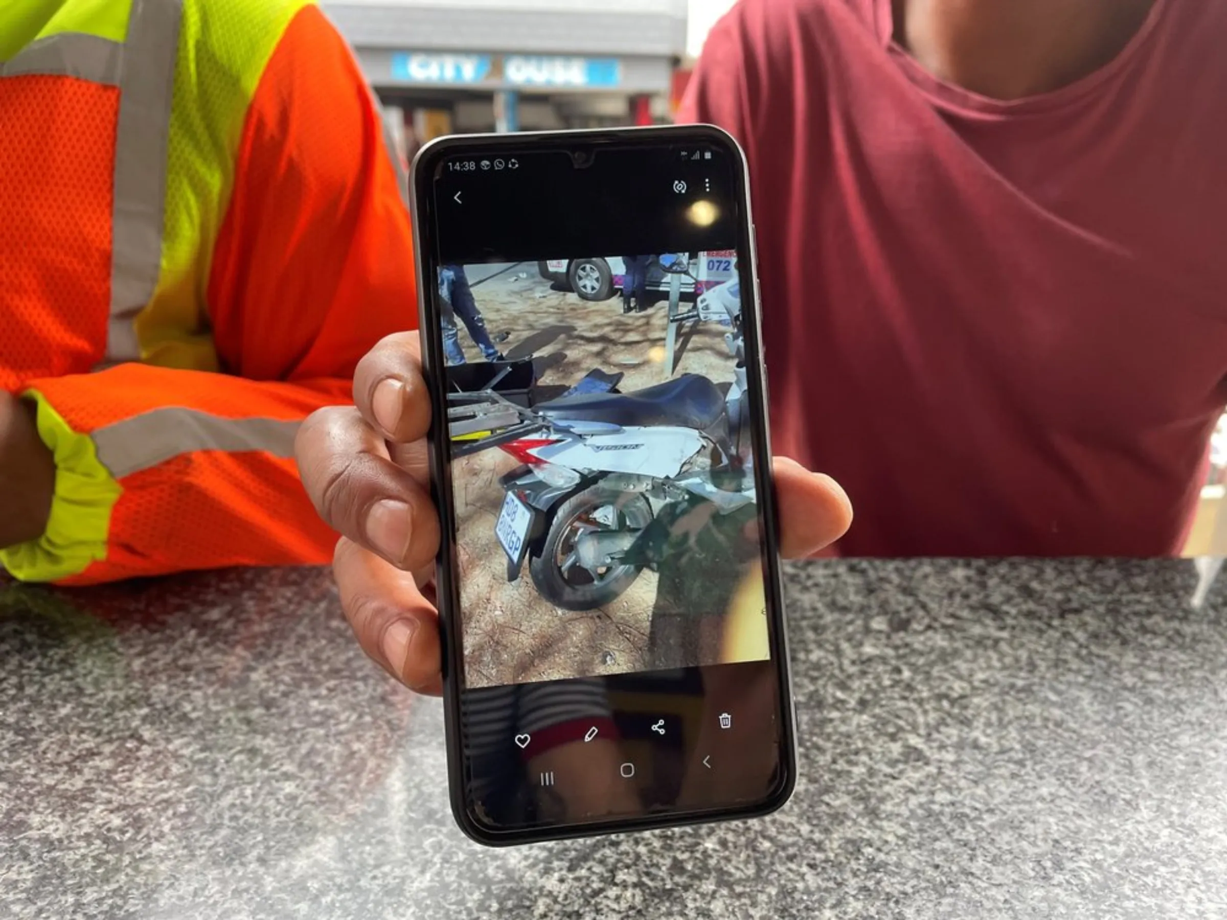 Zimbabwean driver Carl shows a photo on his phone of his dented motorcycle after many accidents in Pretoria, South Africa. February 9, 2020. Thomson Reuters Foundation/Kim Harrisberg