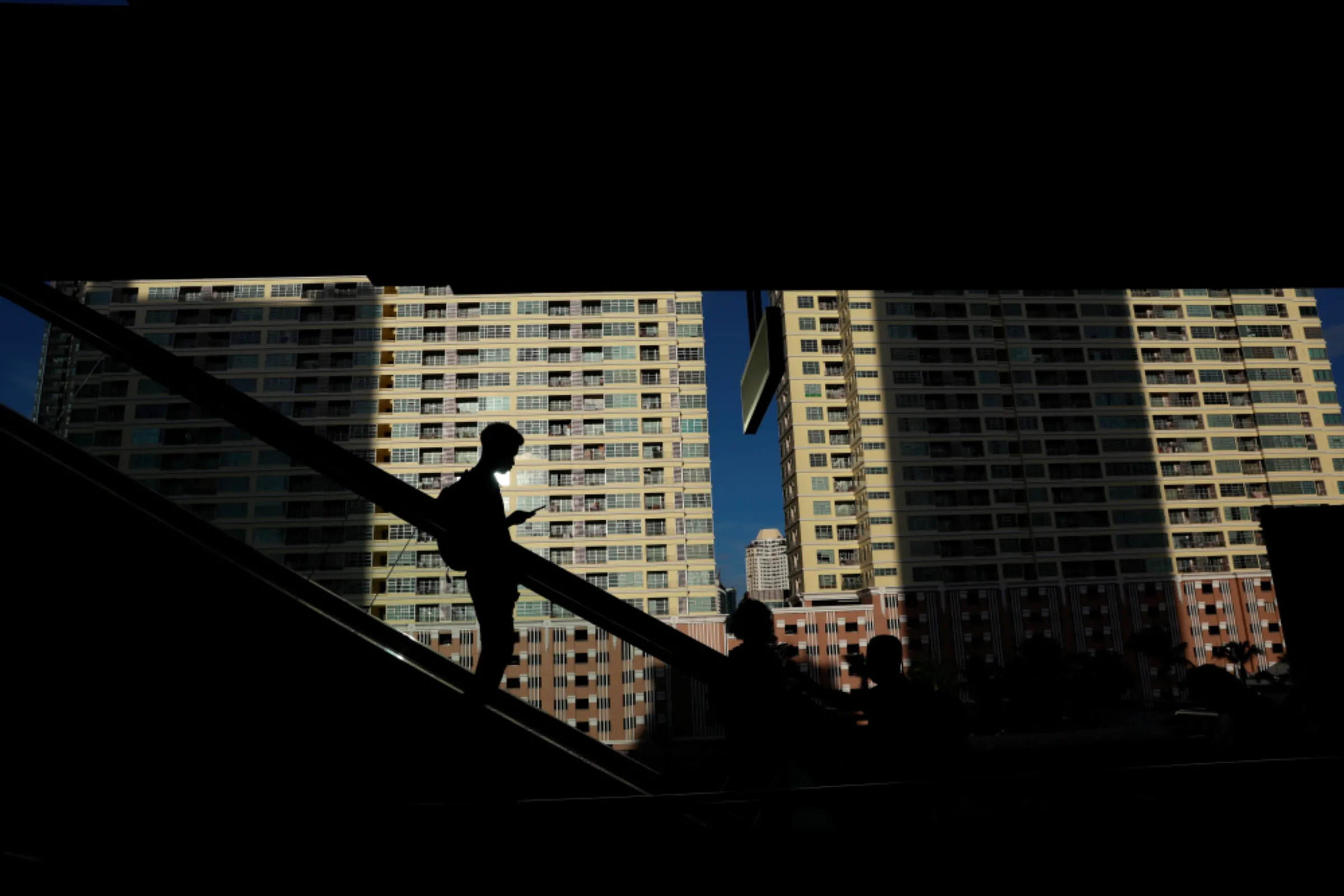 A man uses his phone on an escalator at train station in Bangkok, Thailand July 29, 2019