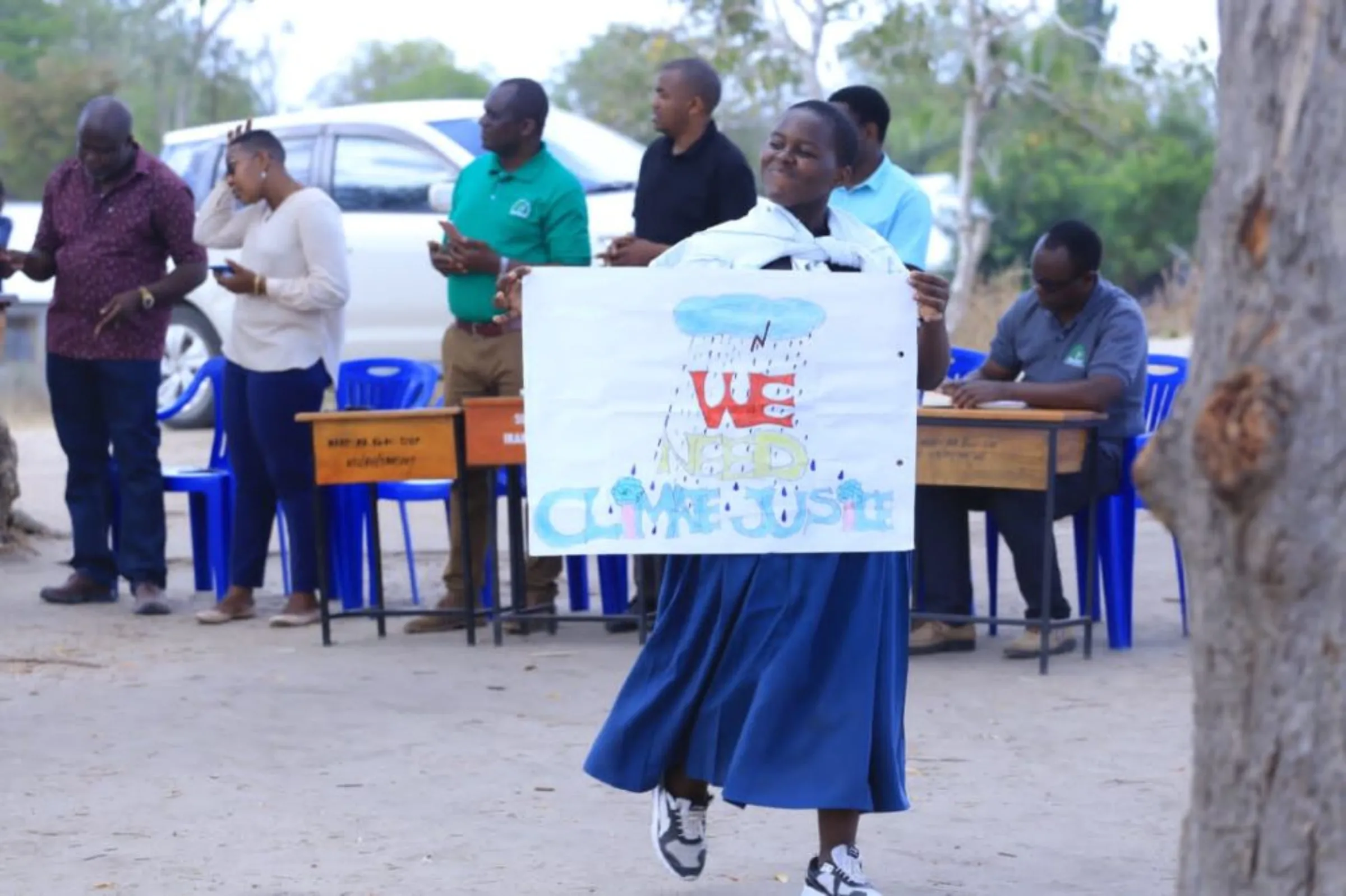 A student smiles while holding a climate protest sign at her school in the Kibaha district, Tanzania, October 9, 2022