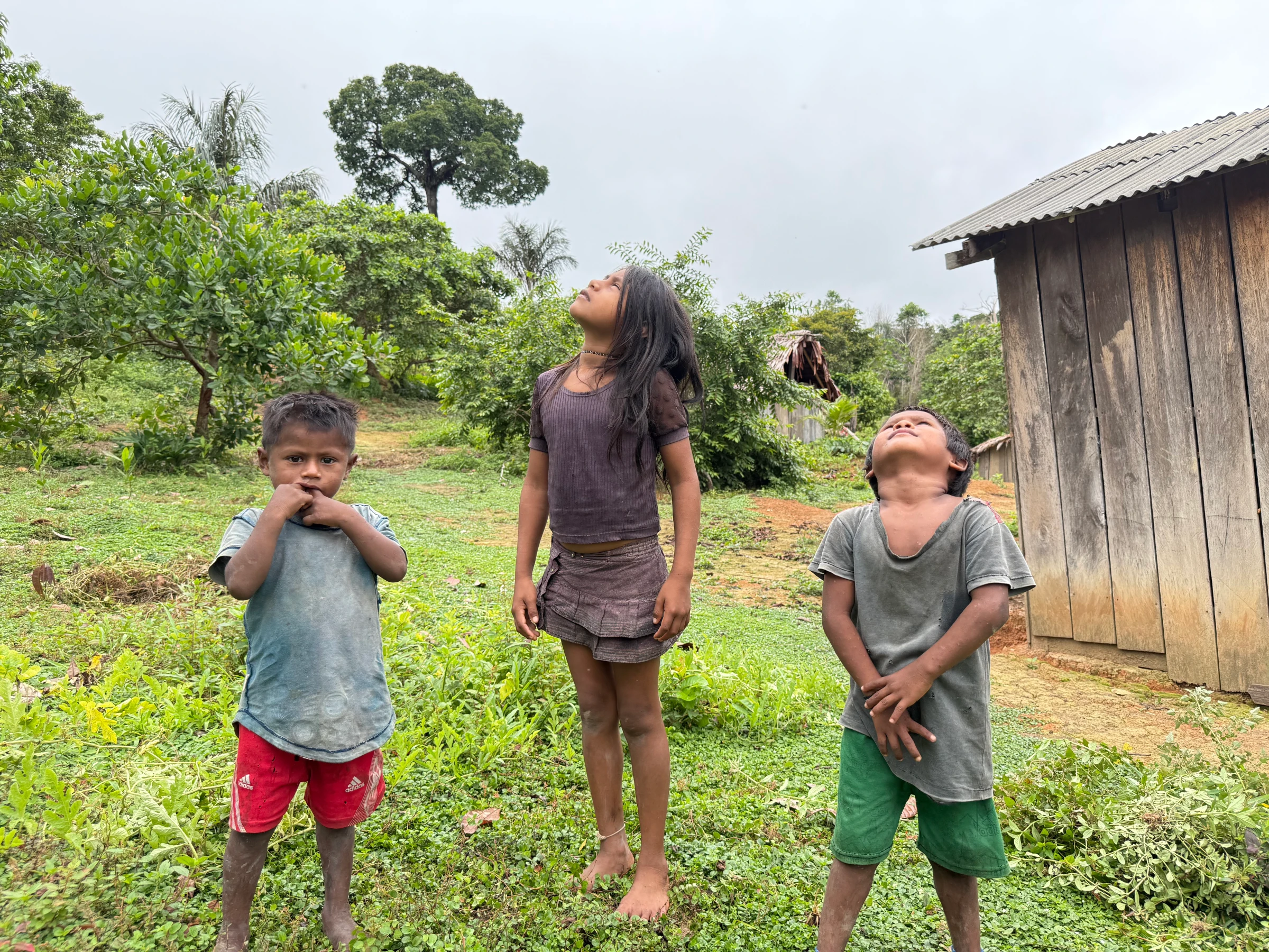 Munduruku children watch a drone flown by troops in search of mining sites as it flies overhead in the Munduruku Indigenous Reserve, Brazil, Jan 9, 2025. Thomson Reuters Foundation/Dan Collyns