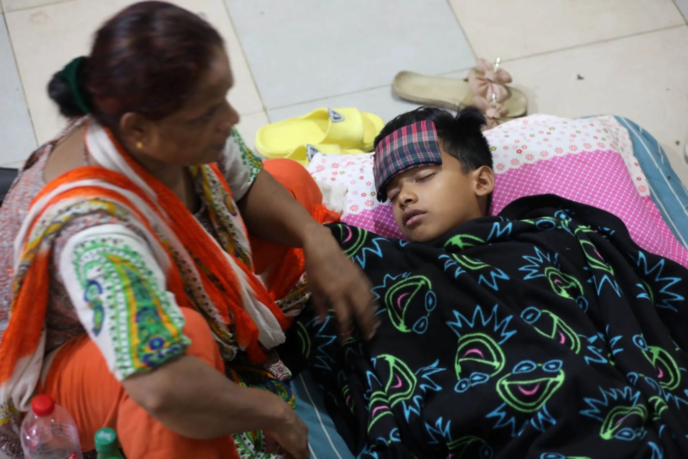 A grandmother keeps her vigil at the side of her sick grandchild at the dengue wards at the Mugda Medical College and Hospital, Dhaka, ‎August ‎30, ‎2023