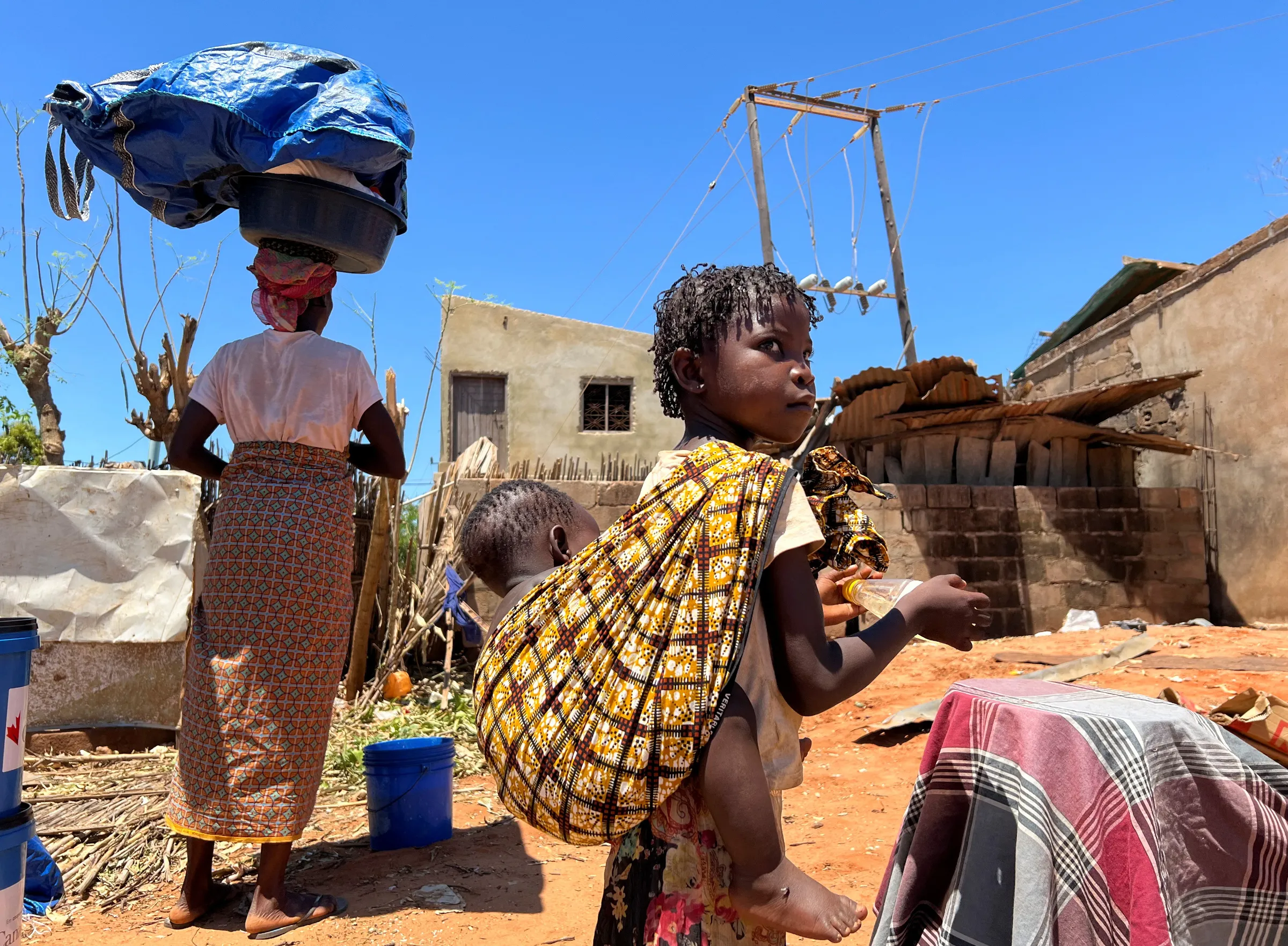 A woman and her children return to their damaged house after cyclone Chido in Pemba, Mozambique, December 18, 2024. REUTERS/Shafiek Tassiem