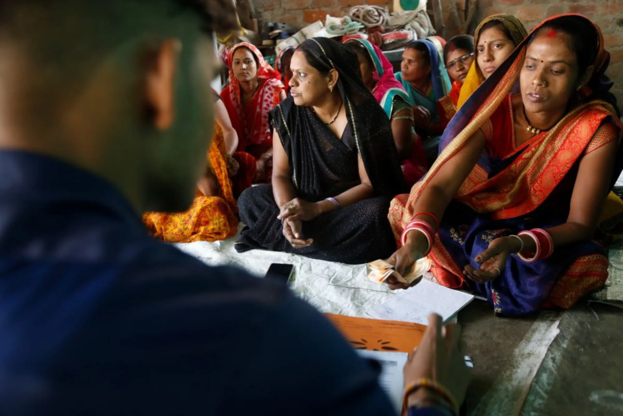 A woman borrower hands over her loan installment to a worker from microfinance company Spandana Sphoorty Financial Limited in her village Narela, Madhya Pradesh, November 10, 2022