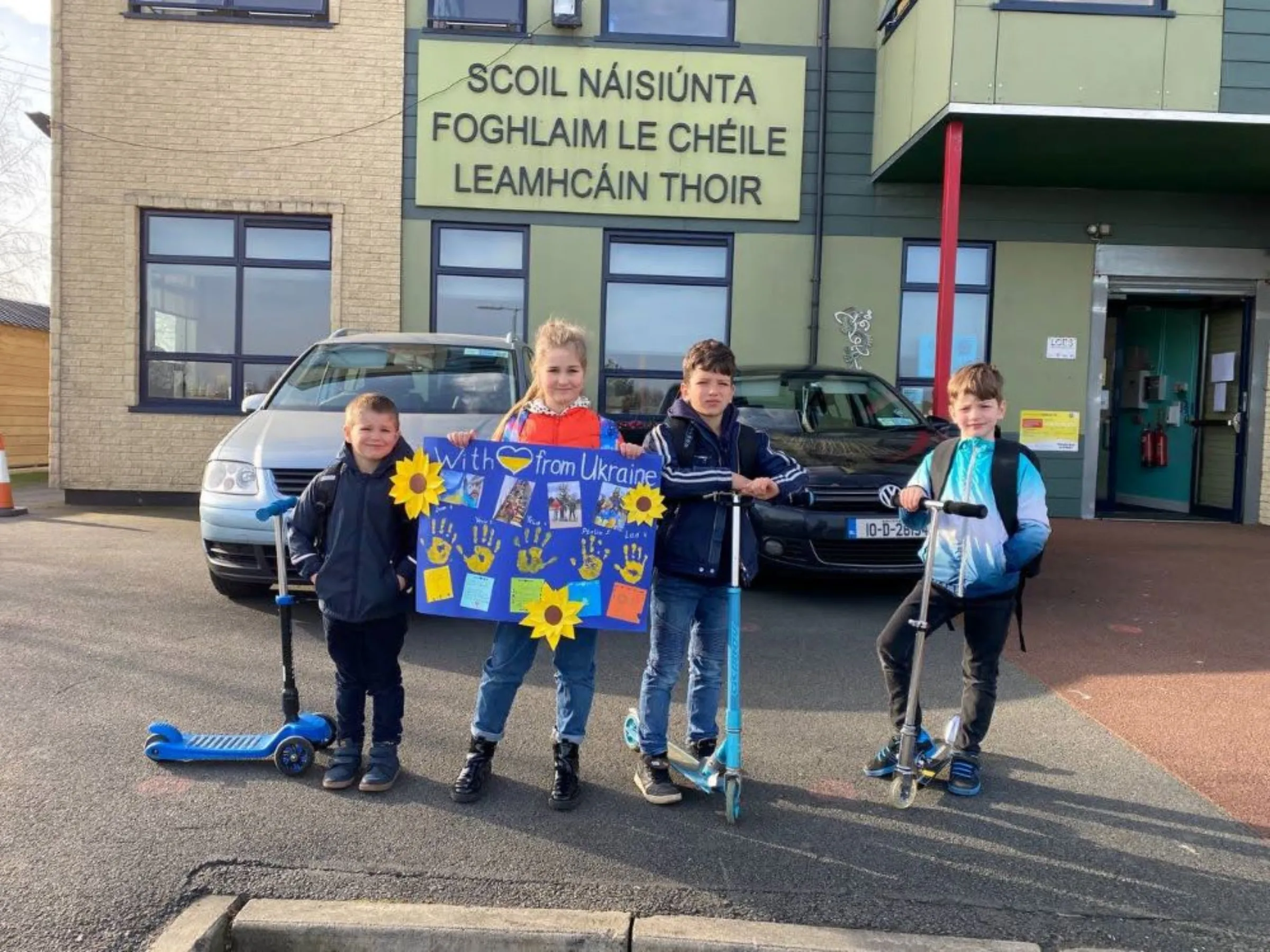 Ukrainian refugee children Varvara Koslovska, 8, brother Platon Koslovskyi, 5, and cousin Ivan Koslovskyi, 9, pose with scooters donated by parents at their new primary school on the outskirts of Dublin. March 2022