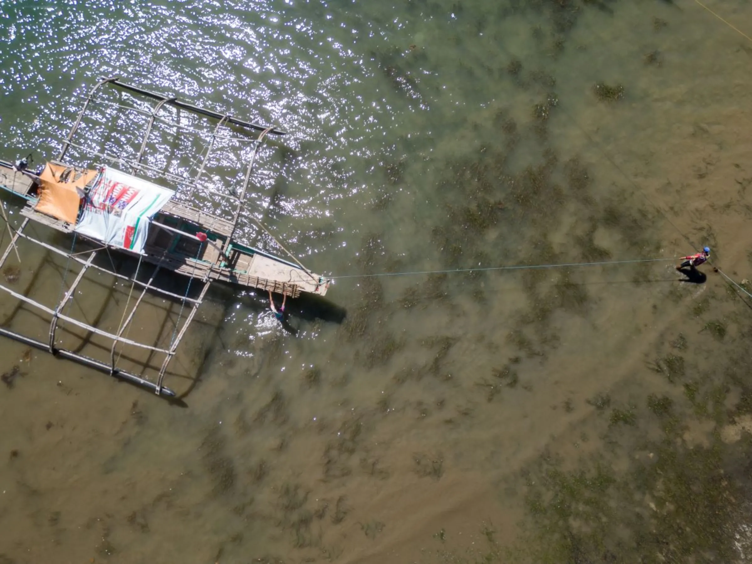 An aerial view of a boat and a fisherman on San Salvador Island, Masinloc in Zambales Province in the Philippines. Fishermen on the island say China’s attempts to block them from fishing at the Scarborough Shoal is costing them money and threatening their livelihoods. Nov. 16, 2023. Thomson Reuters Foundation/Kathleen Limayo