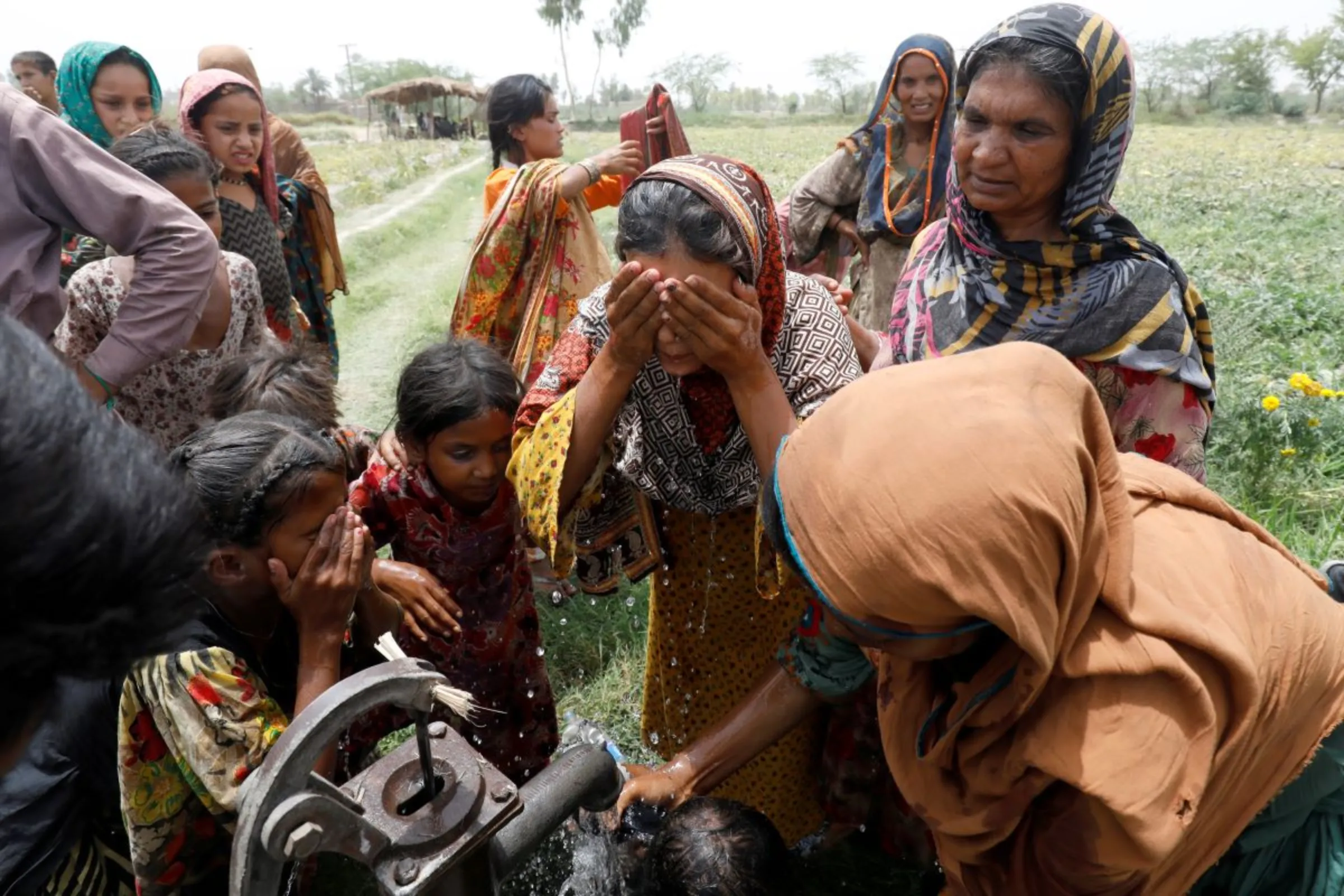 Women and children wash themselves after work at a muskmelon farm in Jacobabad, Pakistan. May 17, 2022. REUTERS/Akhtar Soomro