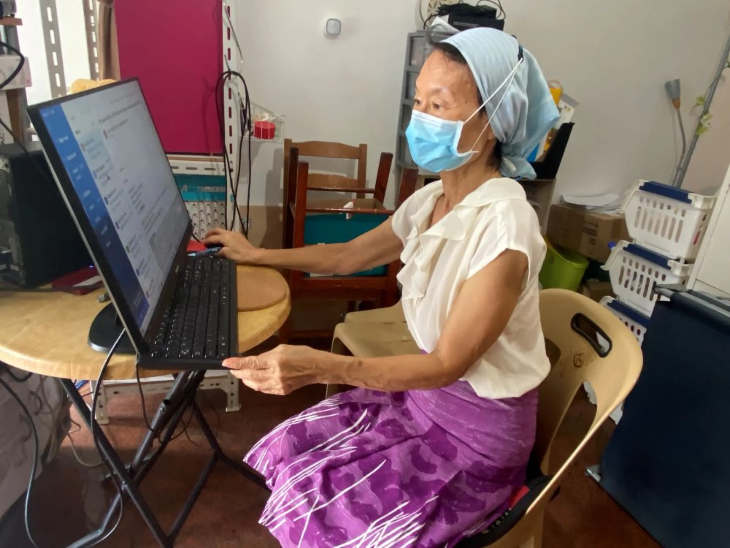 Evelyn, 74, works at her computer near a WiFi motion sensor in her home in Singapore. December 7, 2022. Thomson Reuters Foundation/Rina Chandran