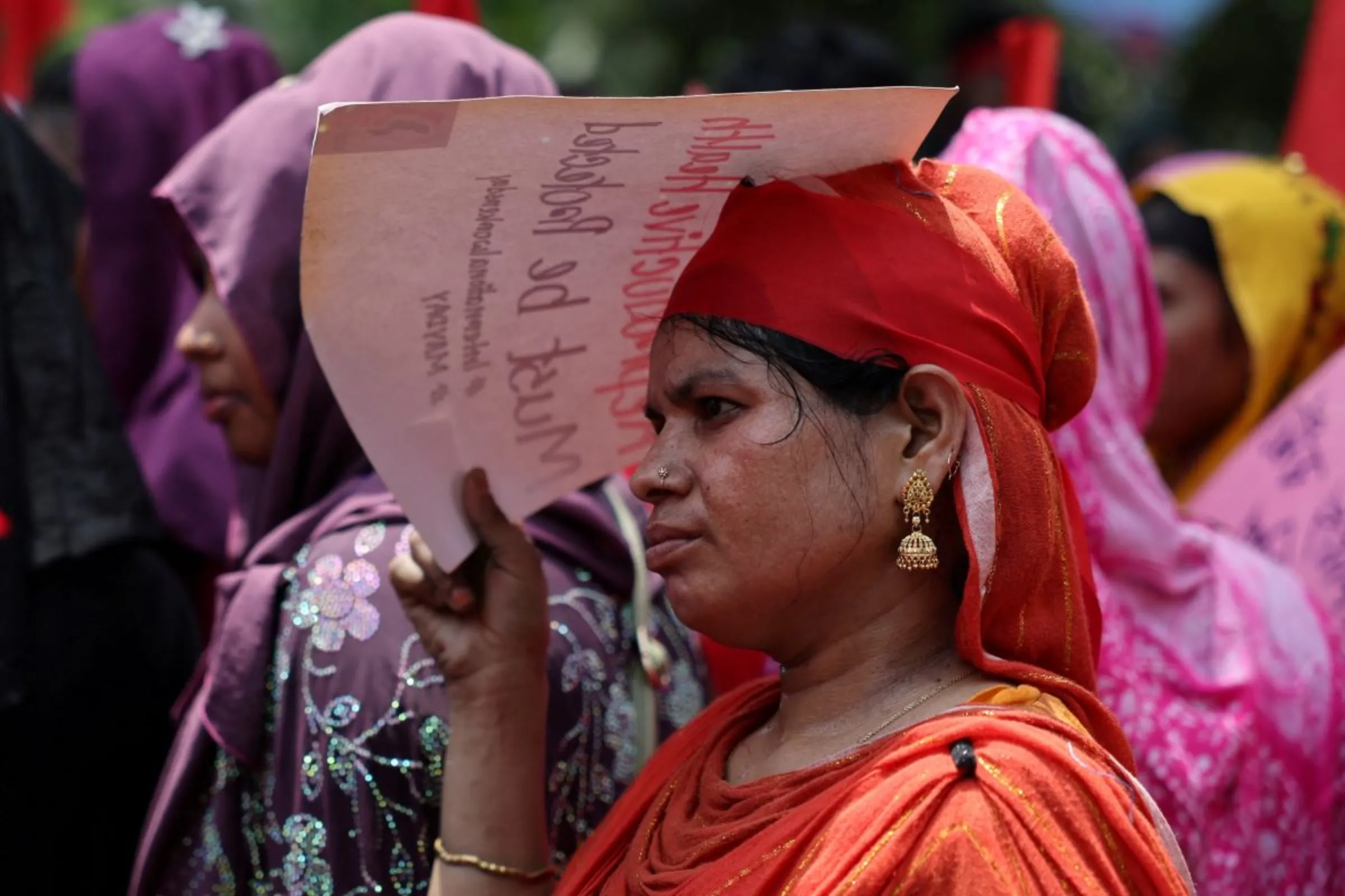 A female worker uses a placard to cover her face from the sun as she joins a protest during the heatwave to mark May Day in Dhaka, Bangladesh, May 1, 2024. REUTERS/Mohammad Ponir Hossain