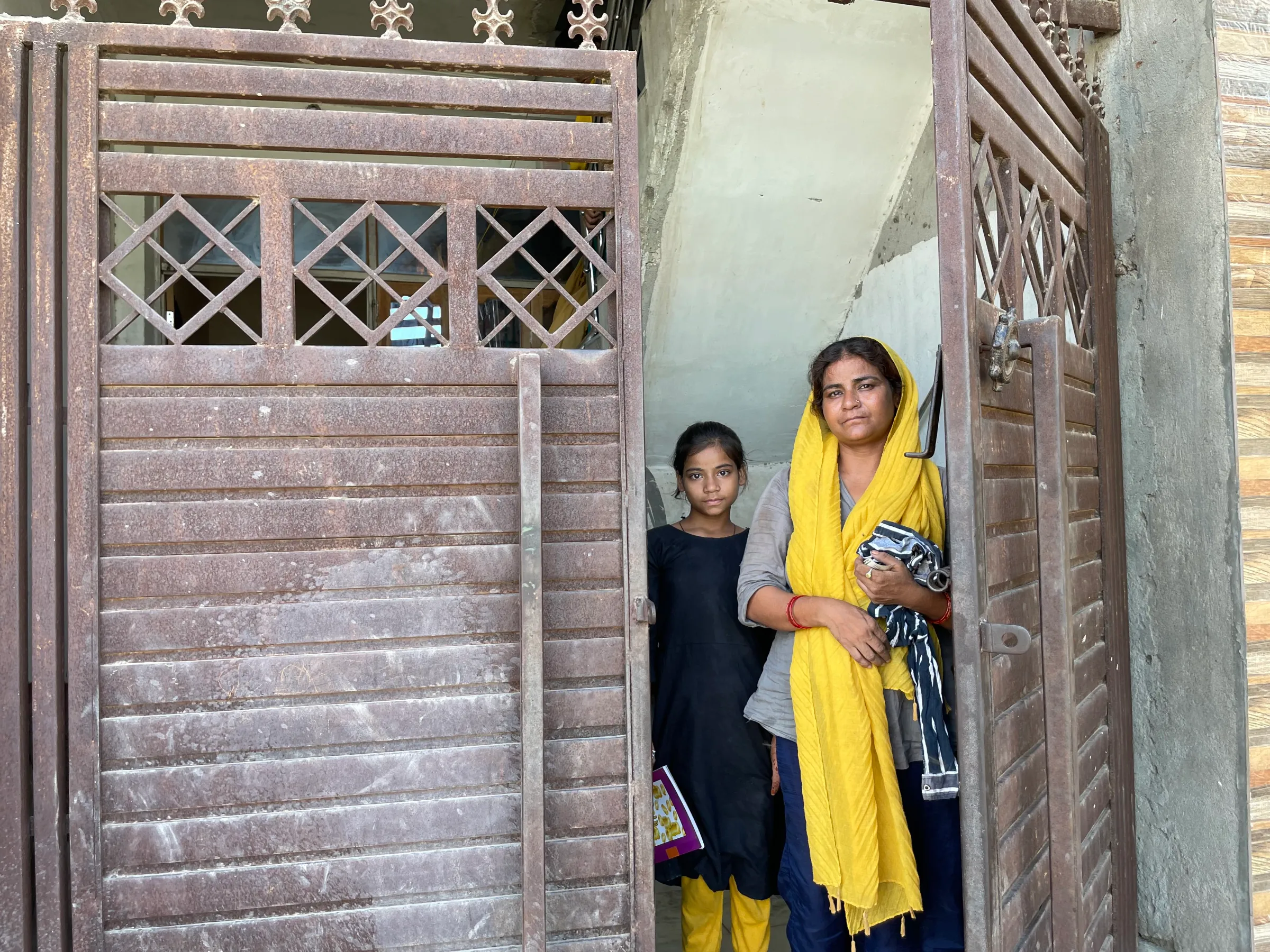 A woman and a child stand at an open gate