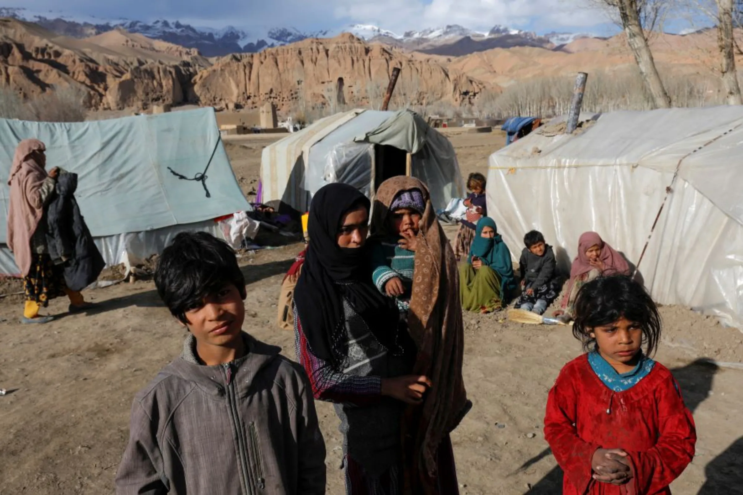A displaced Afghan family from Kunduz province, whose house was destroyed by flood, lives in an open area in front of the ruins of a 1500-year-old Buddha statue, in Bamiyan, Afghanistan, March 2, 2023