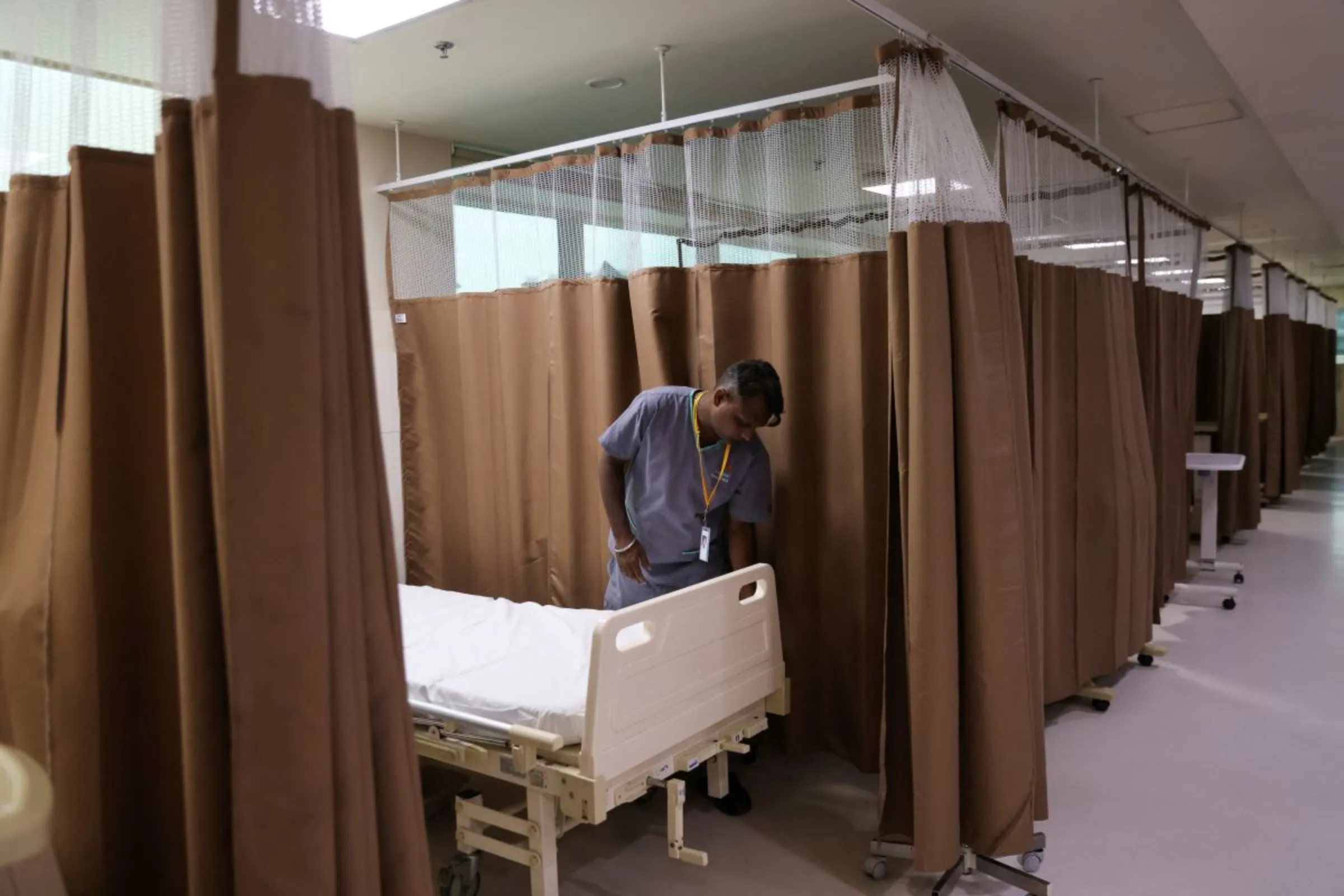 A healthcare worker arranges a bed inside a ward at a hospital in New Delhi, India, June 22, 2023. REUTERS/Anushree Fadnavis