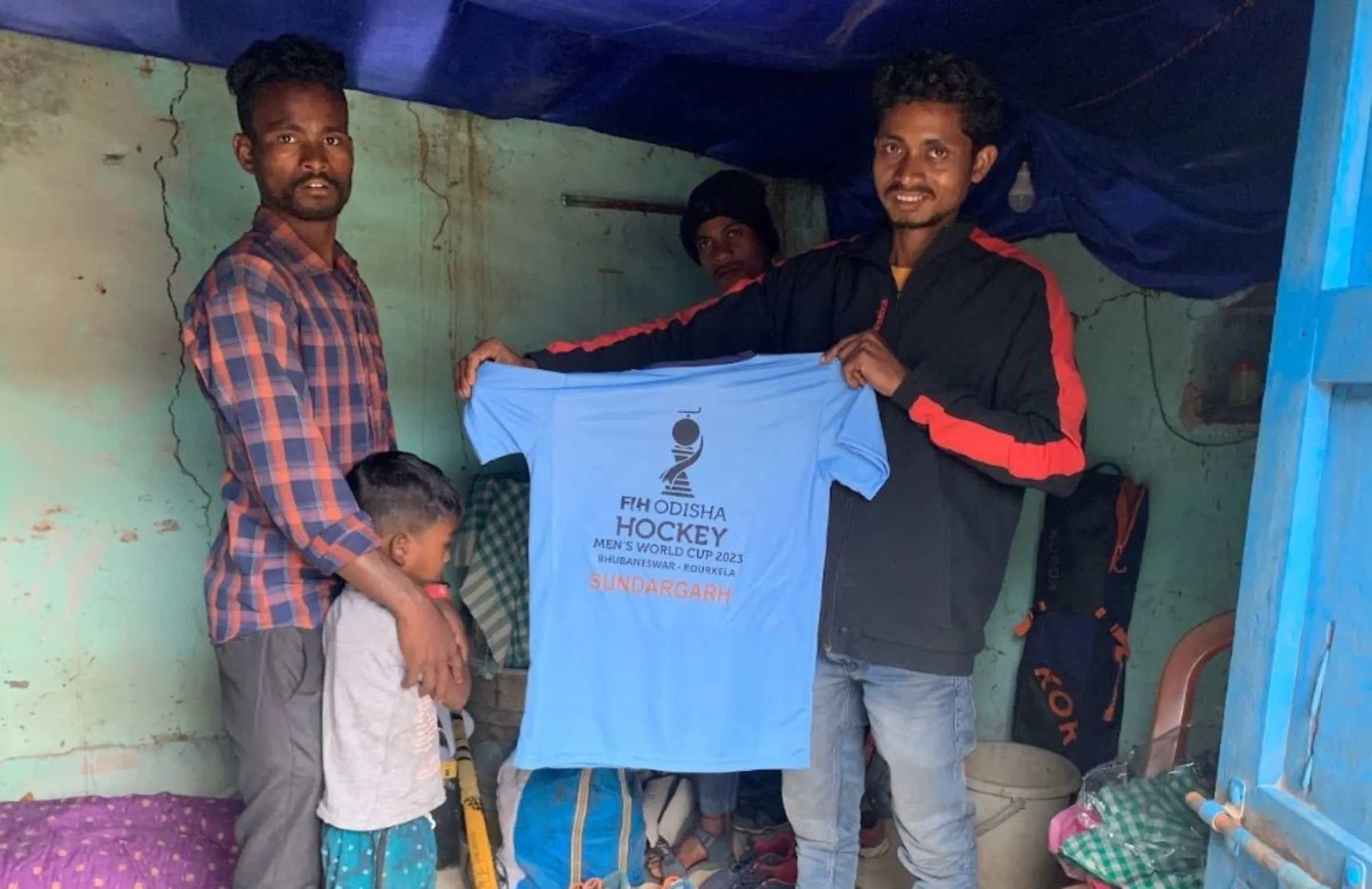 Mahesh Beck (left) and Bimal Ashok Minj pose with a t-shirt for the 2023 men's field hockey World Cup in Sumura village in eastern Odisha, India, December 10, 2022