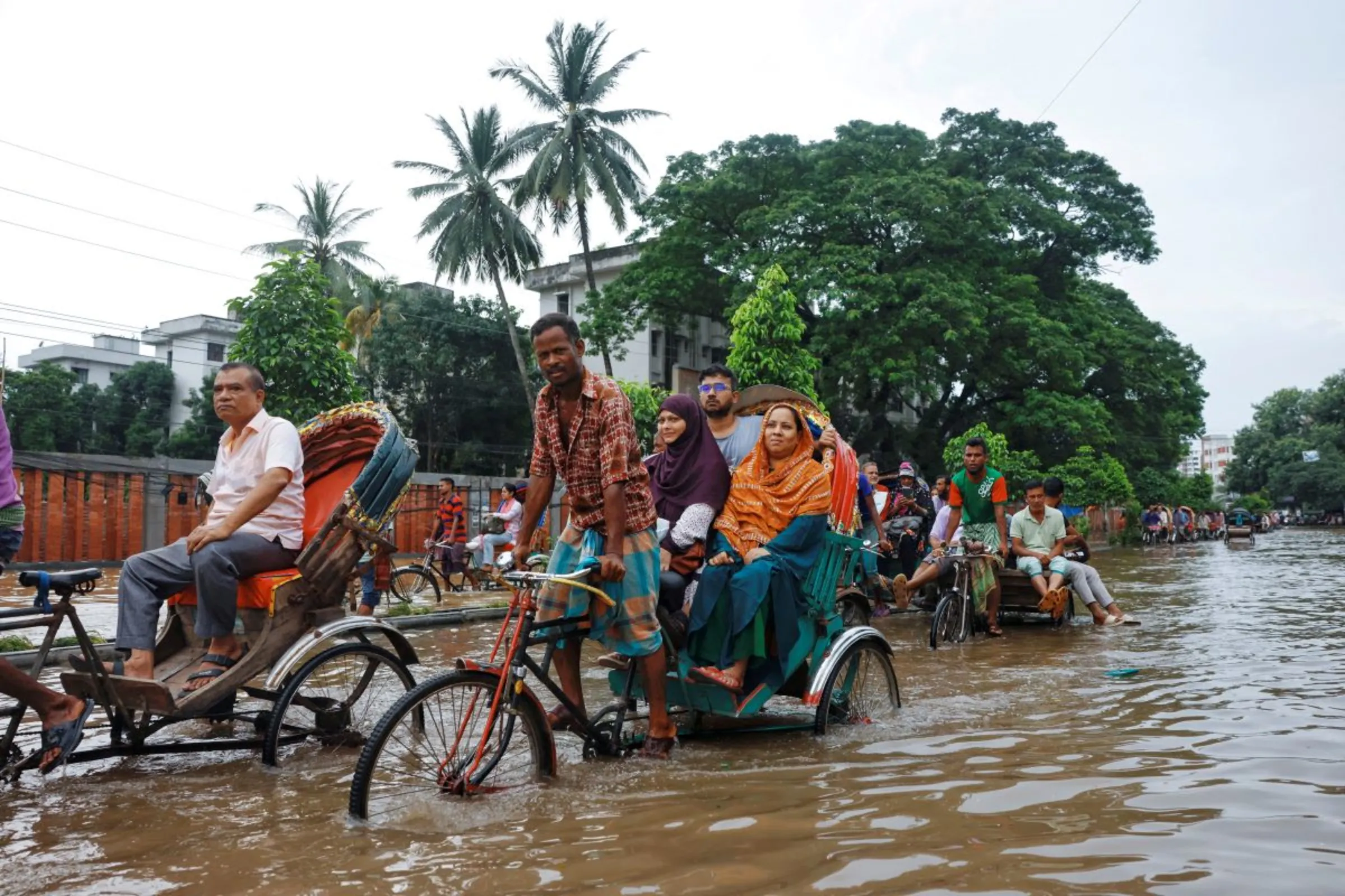 Commuters ride on rickshaws on a flooded road after heavy rains in Dhaka, Bangladesh, September 22, 2023. REUTERS/Mohammad Ponir Hossain