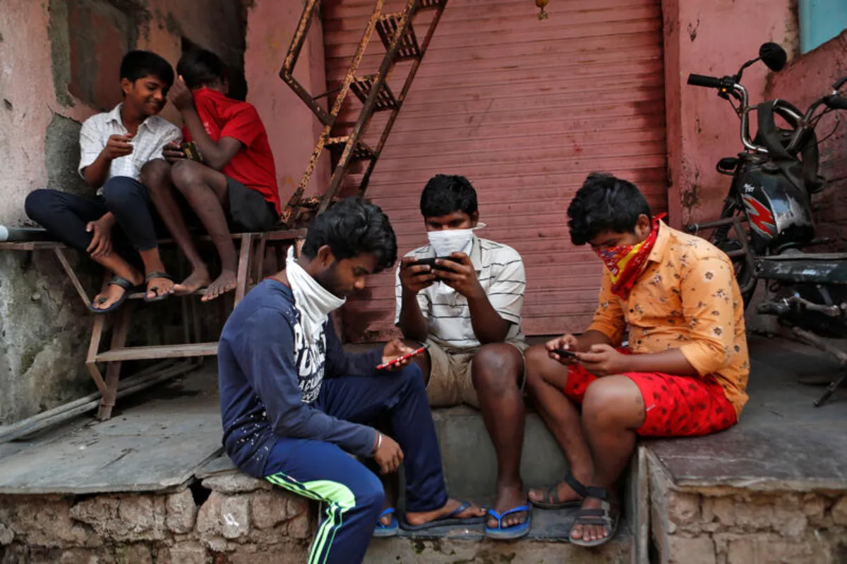 Men look at their mobile phones during a nationwide lockdown in India to slow the spread COVID-19, in Dharavi, Mumbai, India, April 9, 2020. REUTERS/Francis Mascarenhas