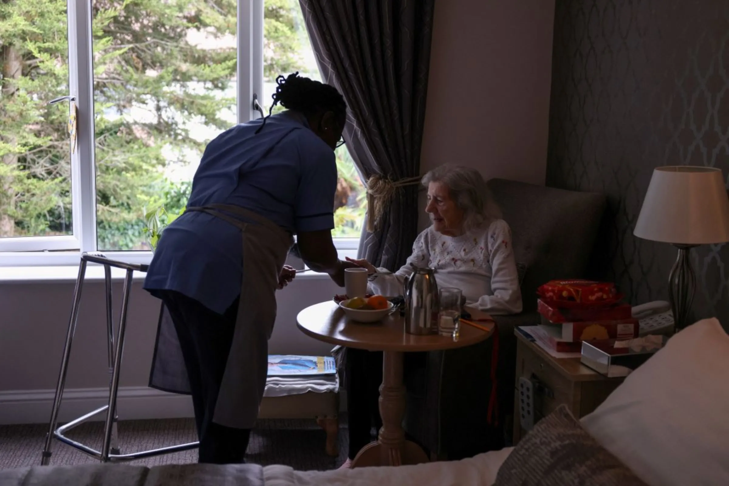A care home worker serves a meal to a resident at a care home in south London, Britain, July 29, 2023. REUTERS/Hollie Adams