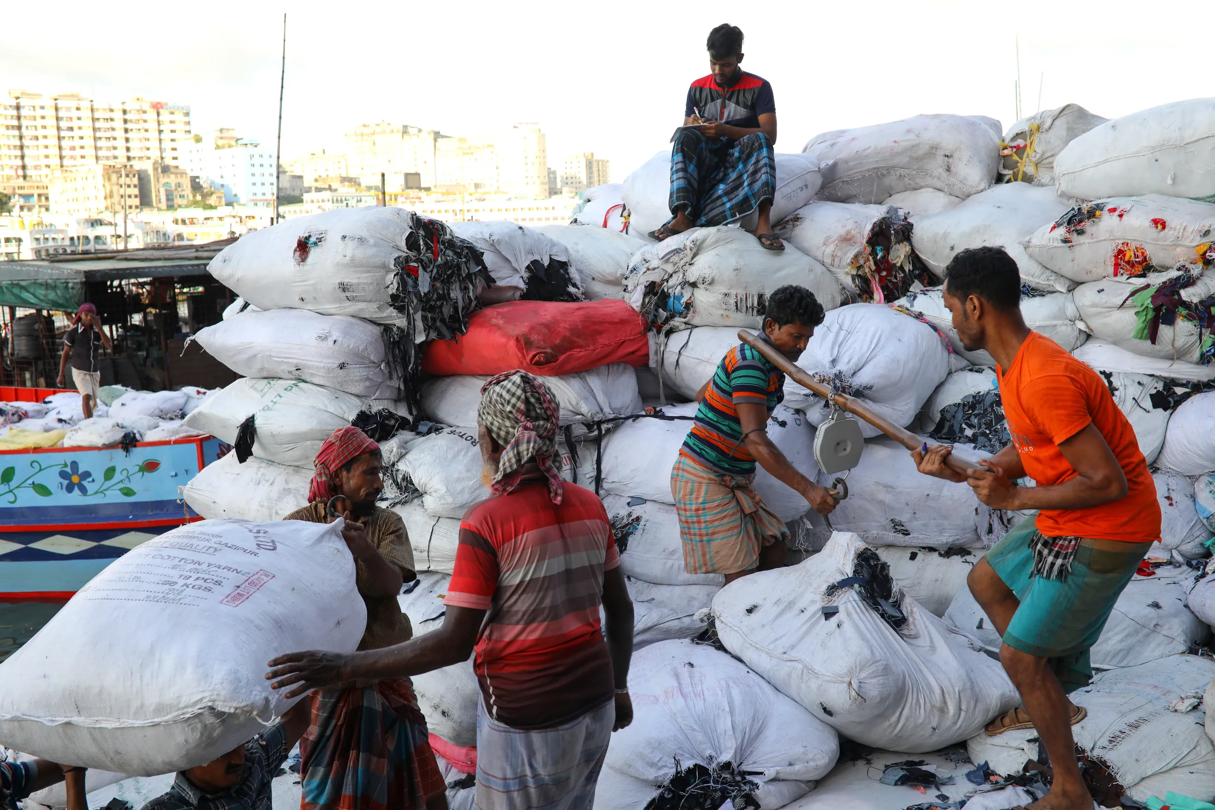 Workers load a ferry with garment waste in Dhaka, Bangladesh, July 28, 2019. REUTERS/Mohammad Ponir Hossain