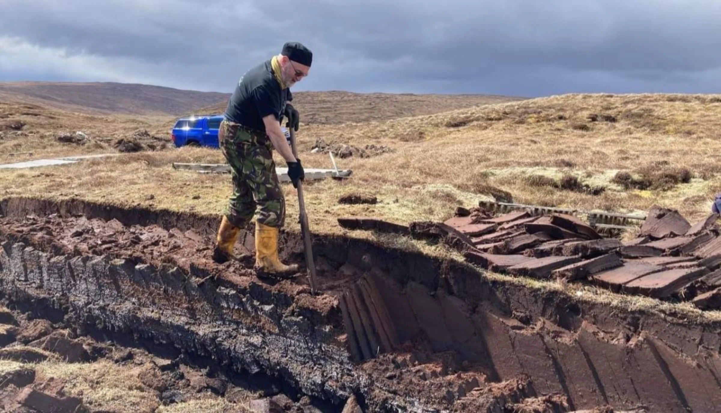 Tour guide and former councillor Drew Ratter cuts a small amount of peat near his house near Ollaberry. Growing up in the 1950s and ‘60s, he said Shetlanders would cut hundreds of bags of peat for fuel, in the summer, in Shetland, Scotland, May 2022. Drew Ratter/Handout via Thomson Reuters Foundation