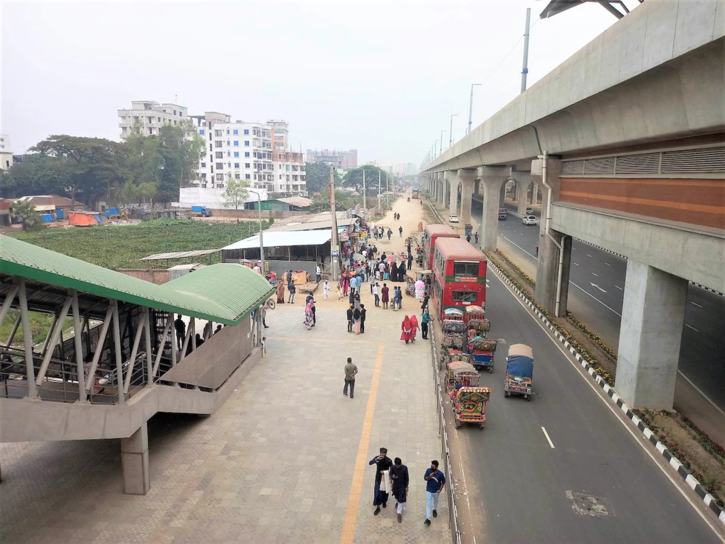 Buses and autorickshaws wait to pick up passengers from a metro rail station in Dhaka, Bangladesh, February 1, 2023. Thomson Reuters Foundation/Md. Tahmid Zami