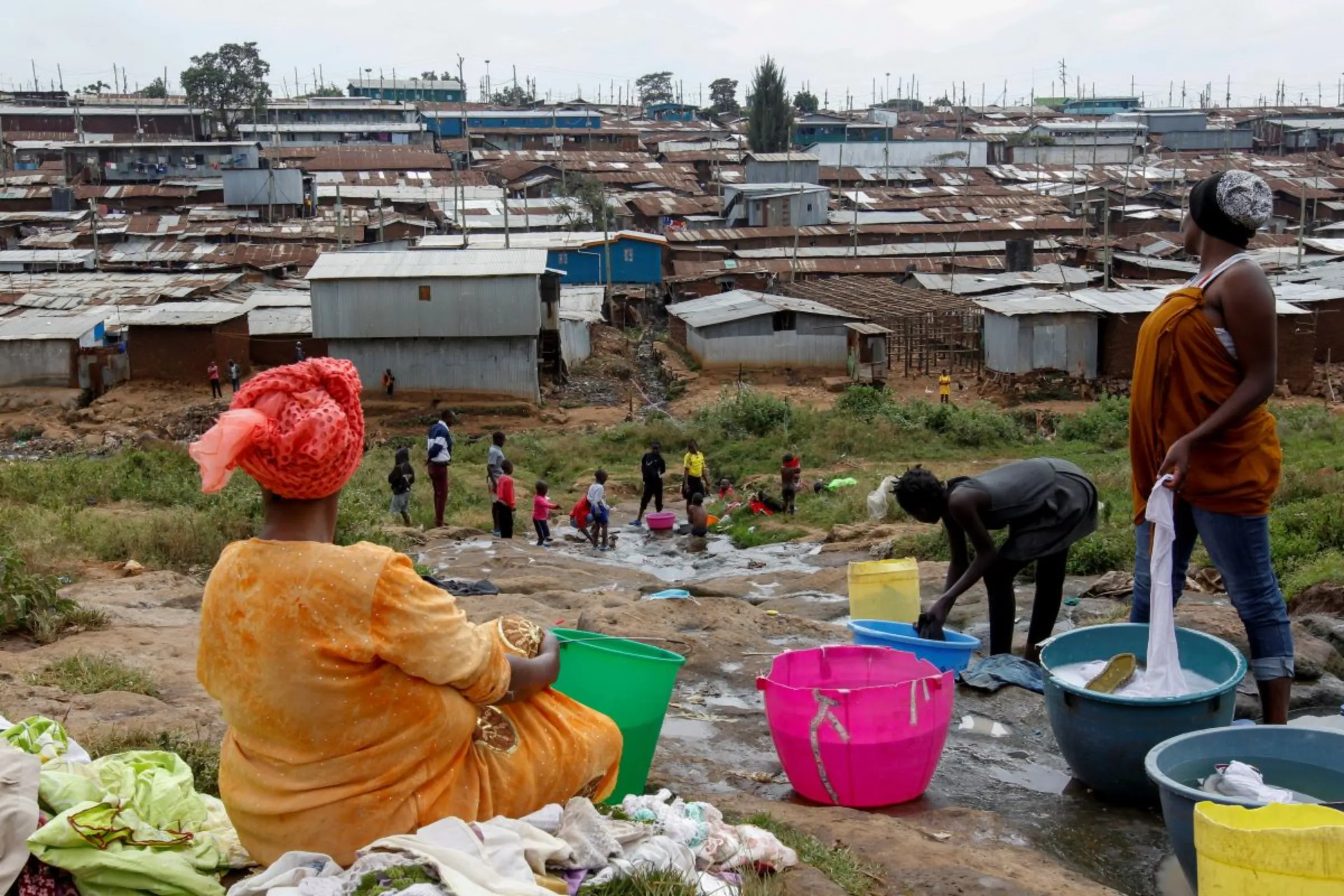 Women wash laundry at a water puddle within the Kibera slums in Nairobi, Kenya, July 21, 2020