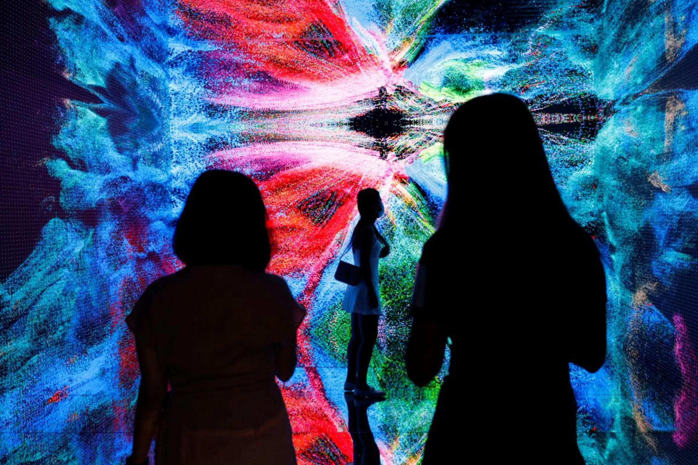 Visitors are pictured in front of an immersive art installation titled 'Machine Hallucinations - Space: Metaverse' by media artist Refik Anadol, in Hong Kong, China