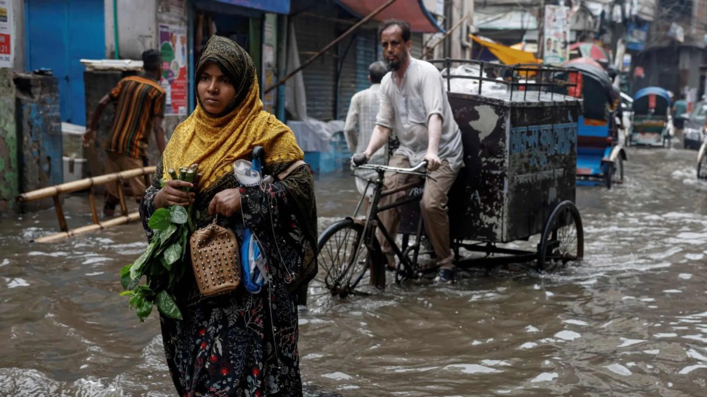 A woman walks along a flooded street after heavy rain, in Dhaka, Bangladesh, June 12, 2023. REUTERS/Mohammad Ponir Hossain