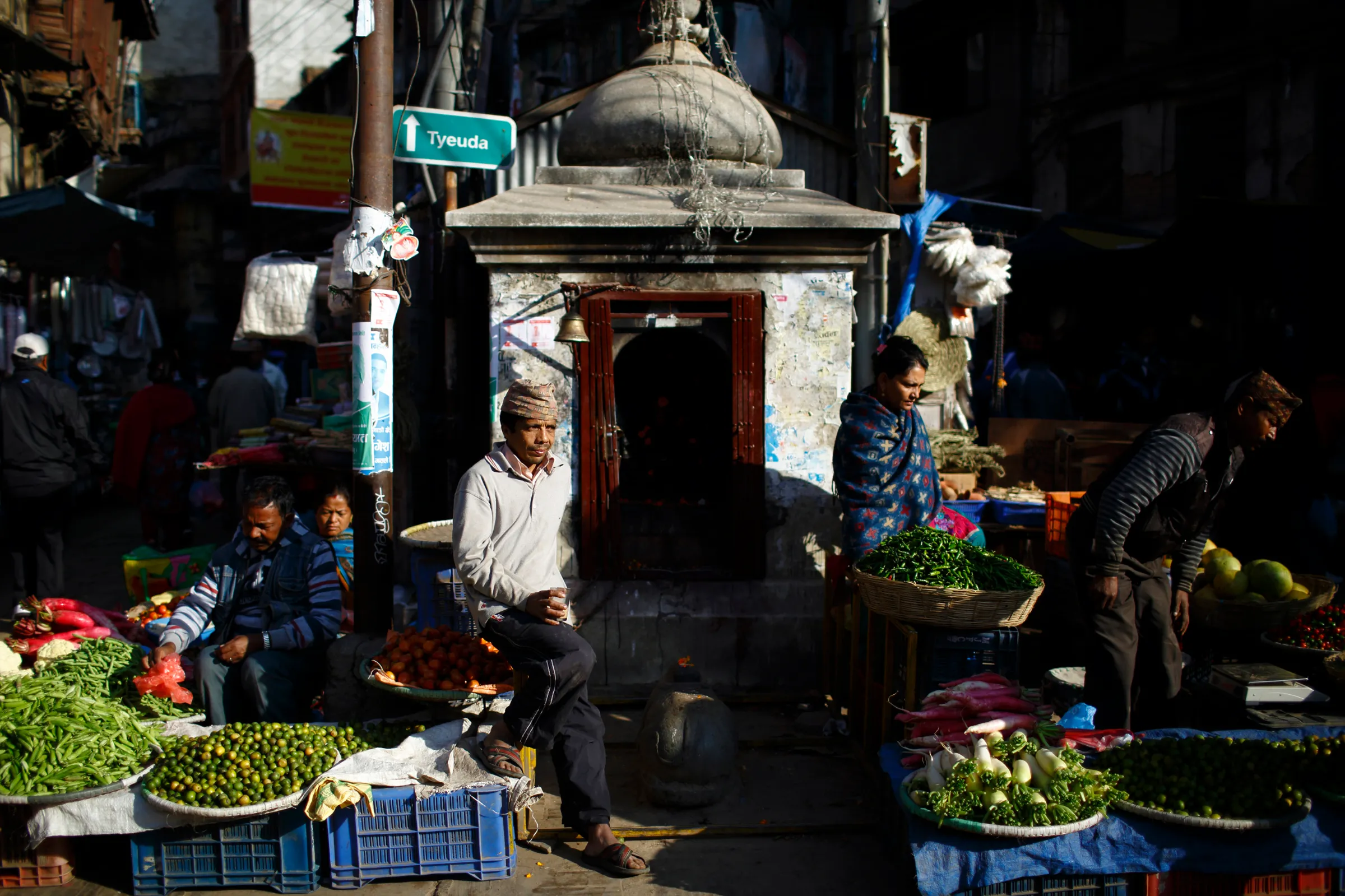 Men and women sell fruit and vegetables at a street market