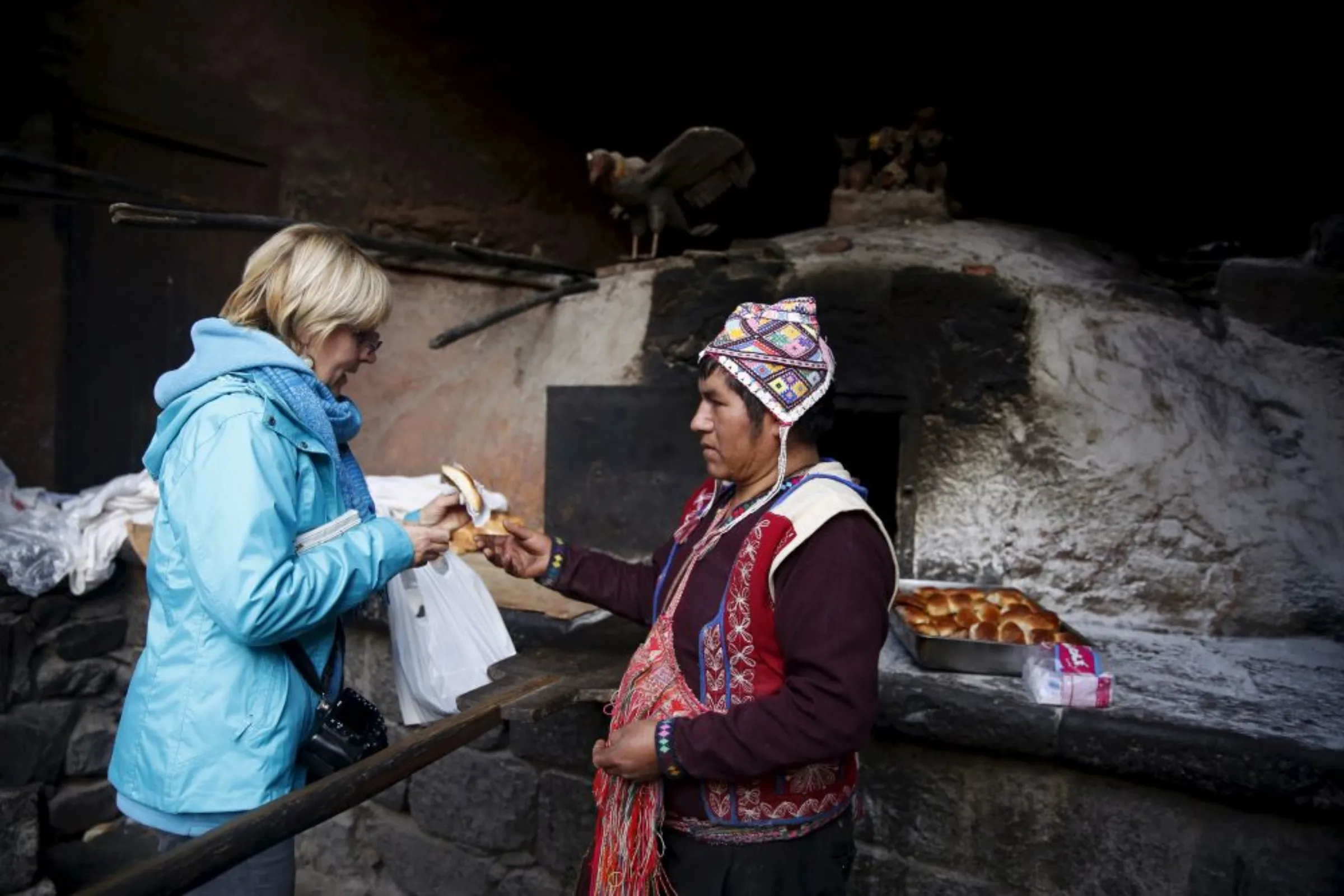 A baker sells traditional empanadas that he baked using an oven made of clay to a tourist in the town of Pisac, Cusco, August 13, 2015