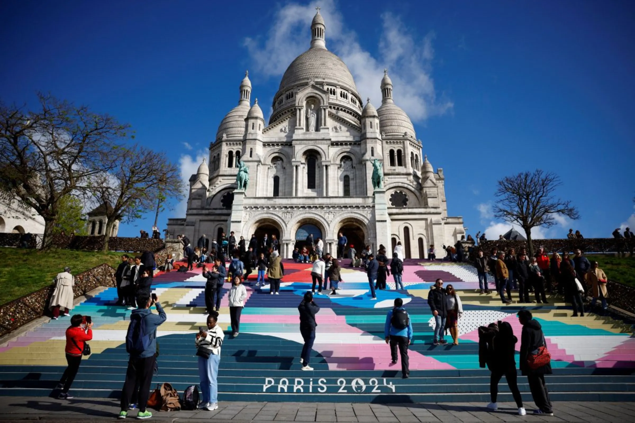 Tourists stand on the Sacre-Coeur Basilica stairs painted with the Paris 2024 Olympic and Paralympic Games design at the Butte Montmartre in Paris, France, April 17, 2024. REUTERS/Sarah Meyssonnier