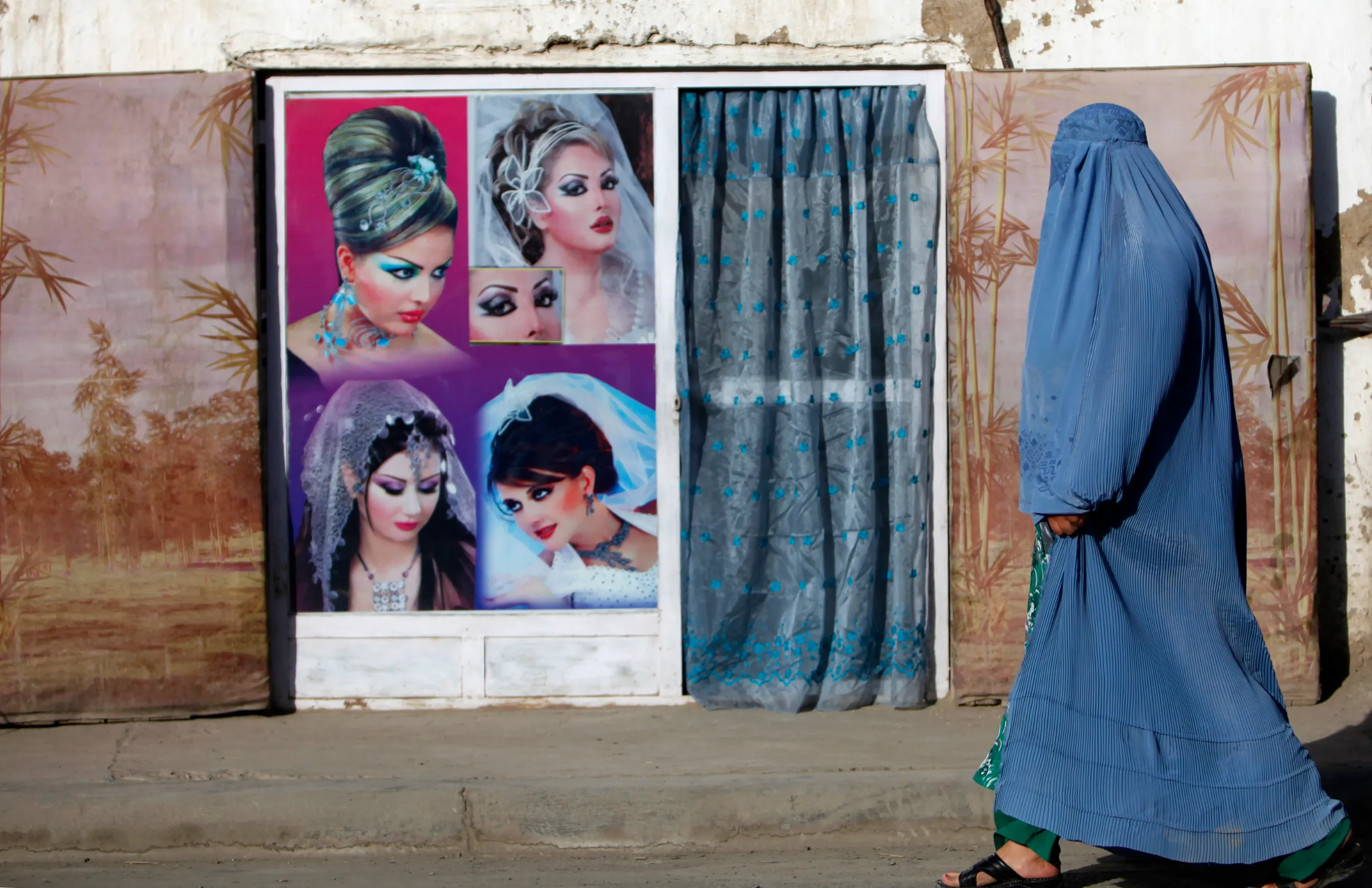 An Afghan woman in a burqa walks past a beauty salon in Kabul September 11, 2013. REUTERS/Mohammad Ismail