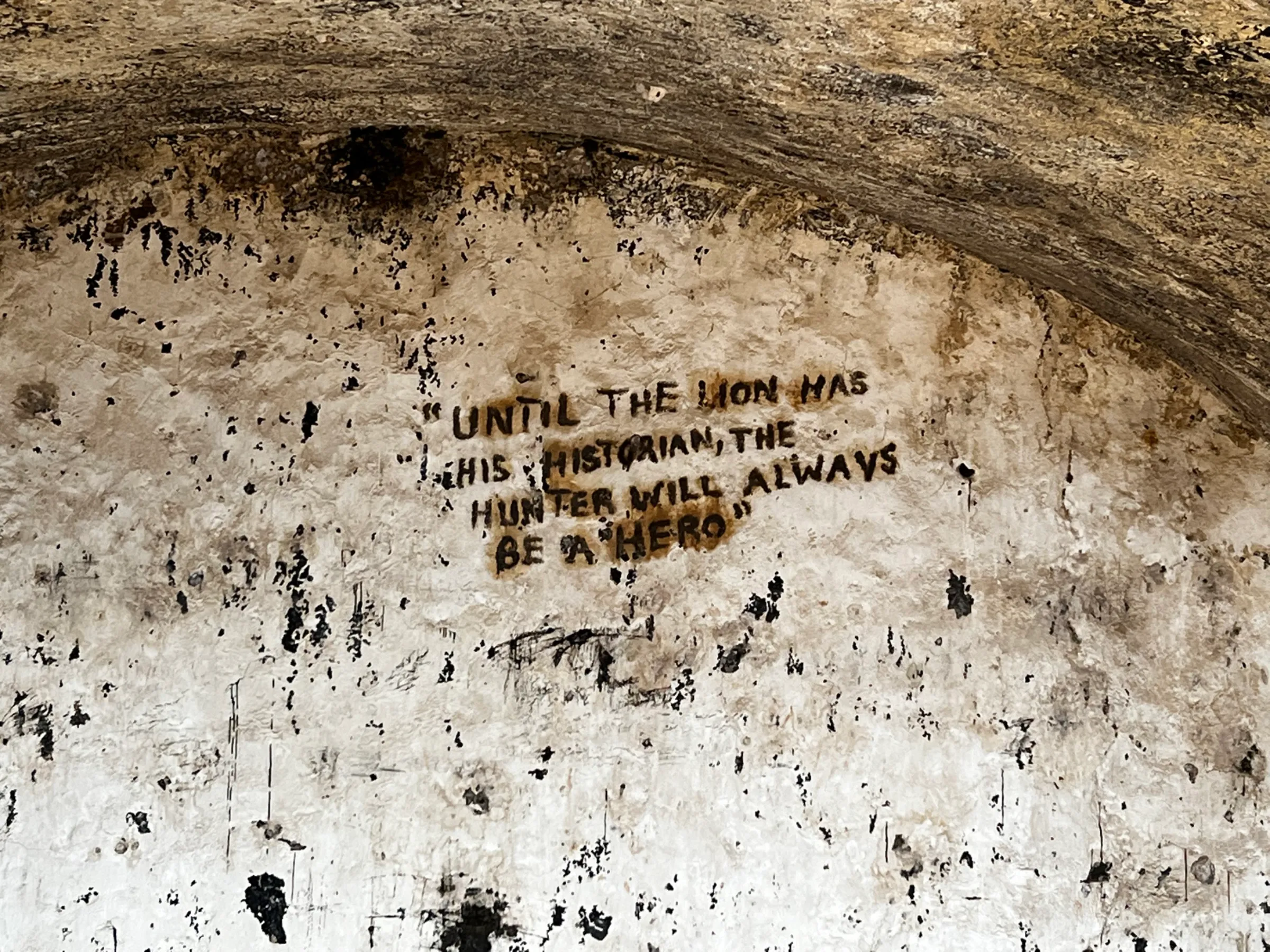 Words etched on the wall of a slave-holding cell at Fort Prinzenstein, an 18th century slave-holding depot, in Keta, Ghana on August 8, 2022. The words read: 'UNTIL THE LION HAS HIS HISTORIAN, THE HUNTER WILL ALWAYS BE A 'HERO'. Thomson Reuters Foundation/Nita Bhalla